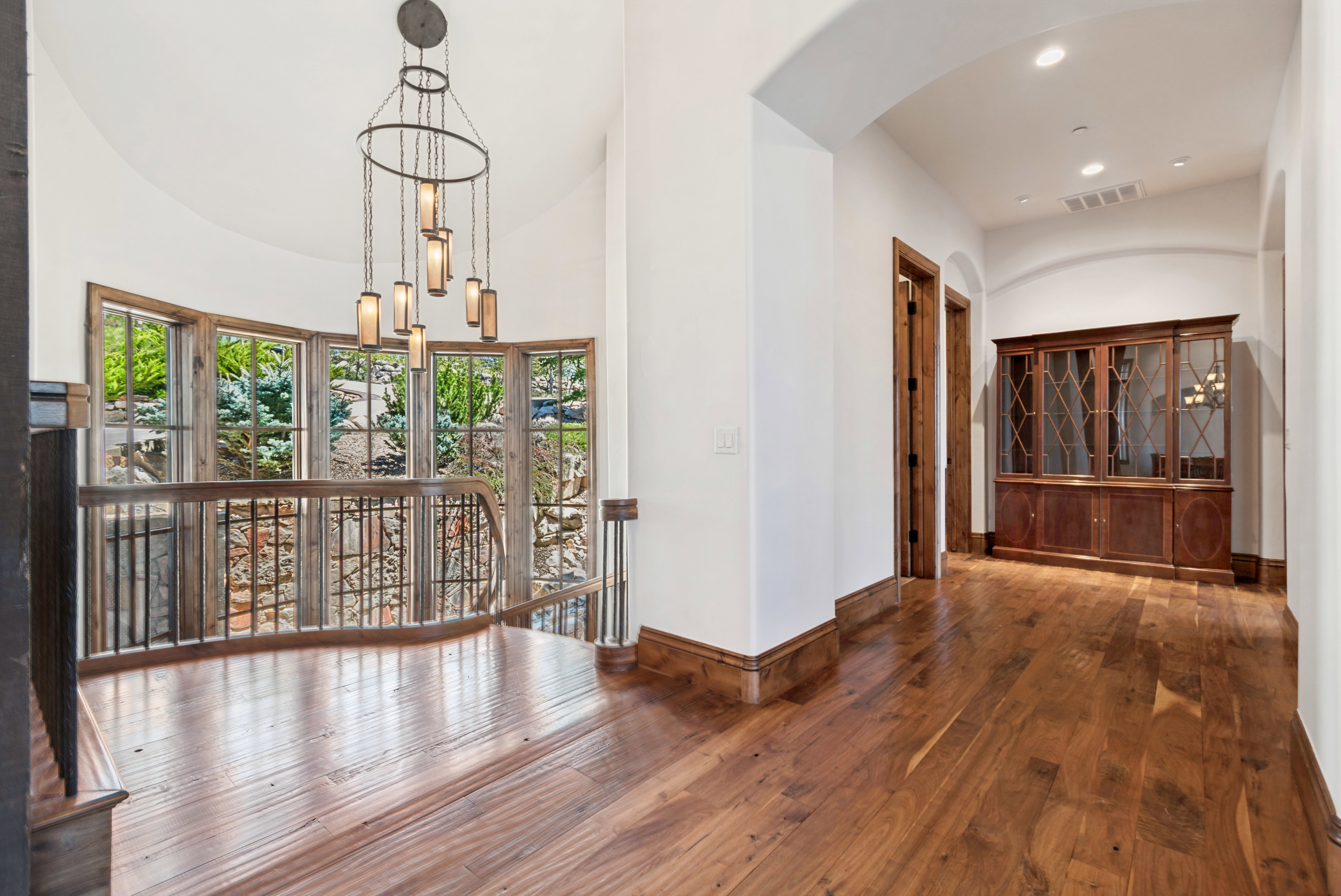 Hardwood flooring throughout a spacious hallway with arched doorways