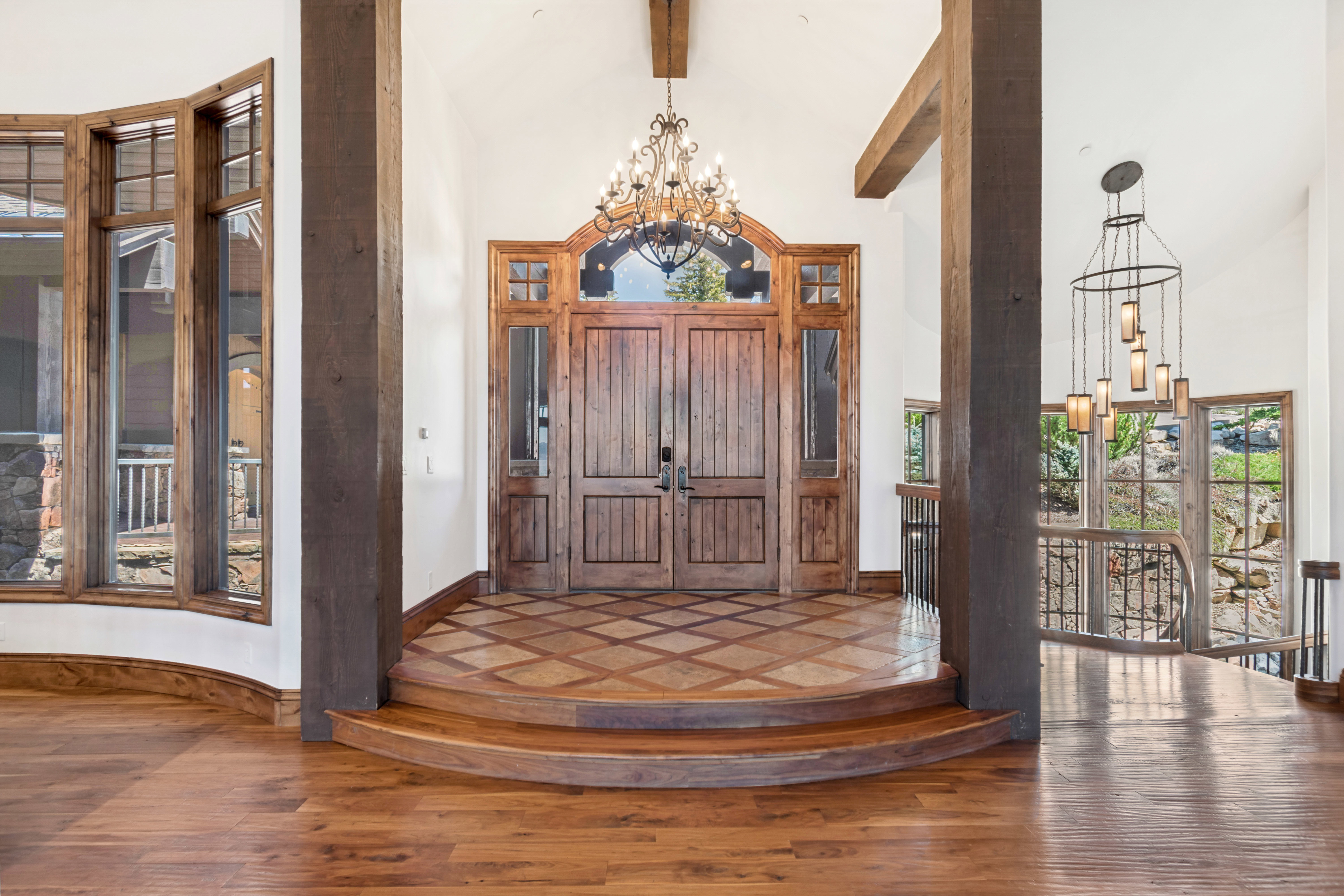 Grand entryway featuring custom wood double doors with sidelights, a decorative arched transom, and an ornate chandelier