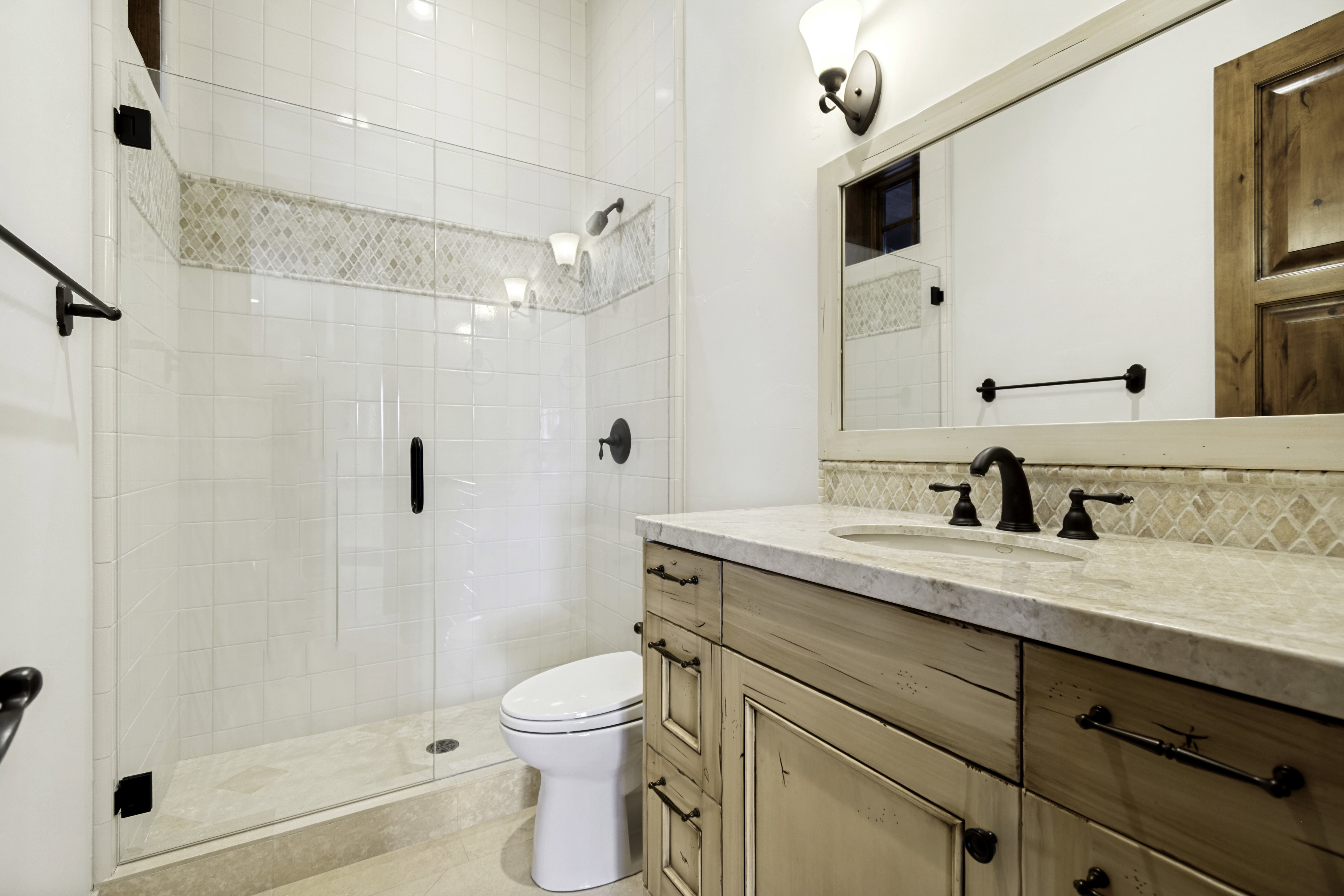 Bathroom featuring a glass-enclosed shower with subway tile surround and decorative accent band