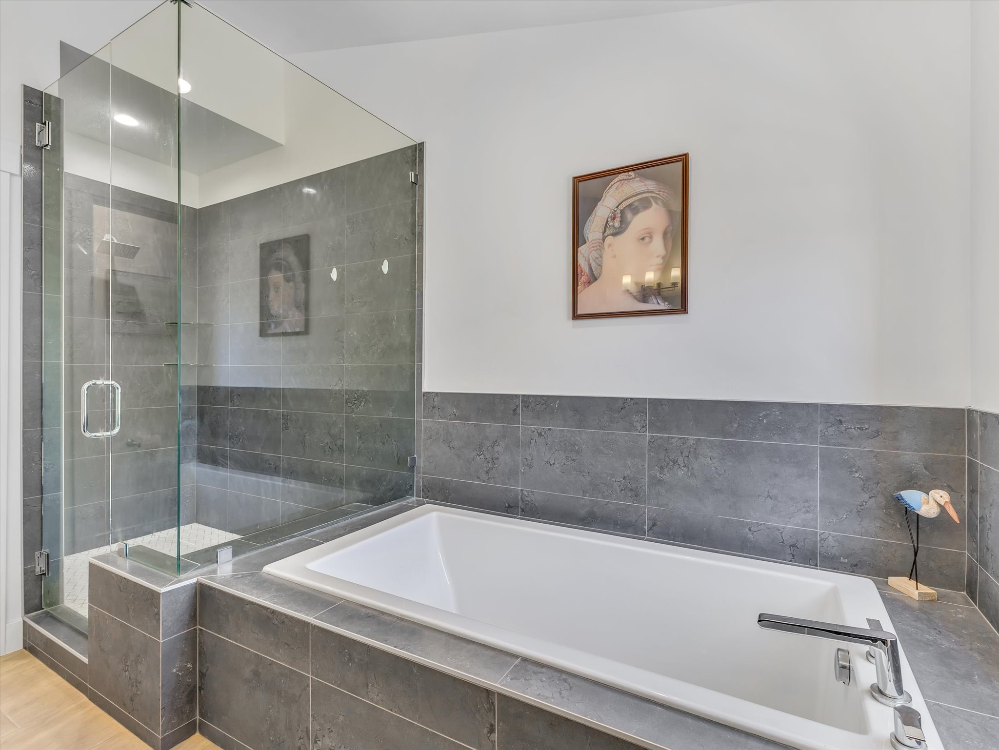 Spacious bathroom featuring a built-in soaking tub, a frameless glass shower enclosure, and grey tile finishes