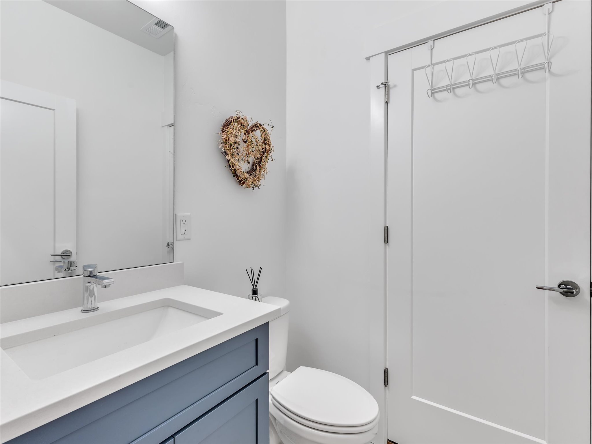 Bathroom featuring a blue vanity with a white countertop and integrated sink, chrome faucet, and a large wall-mounted mirror