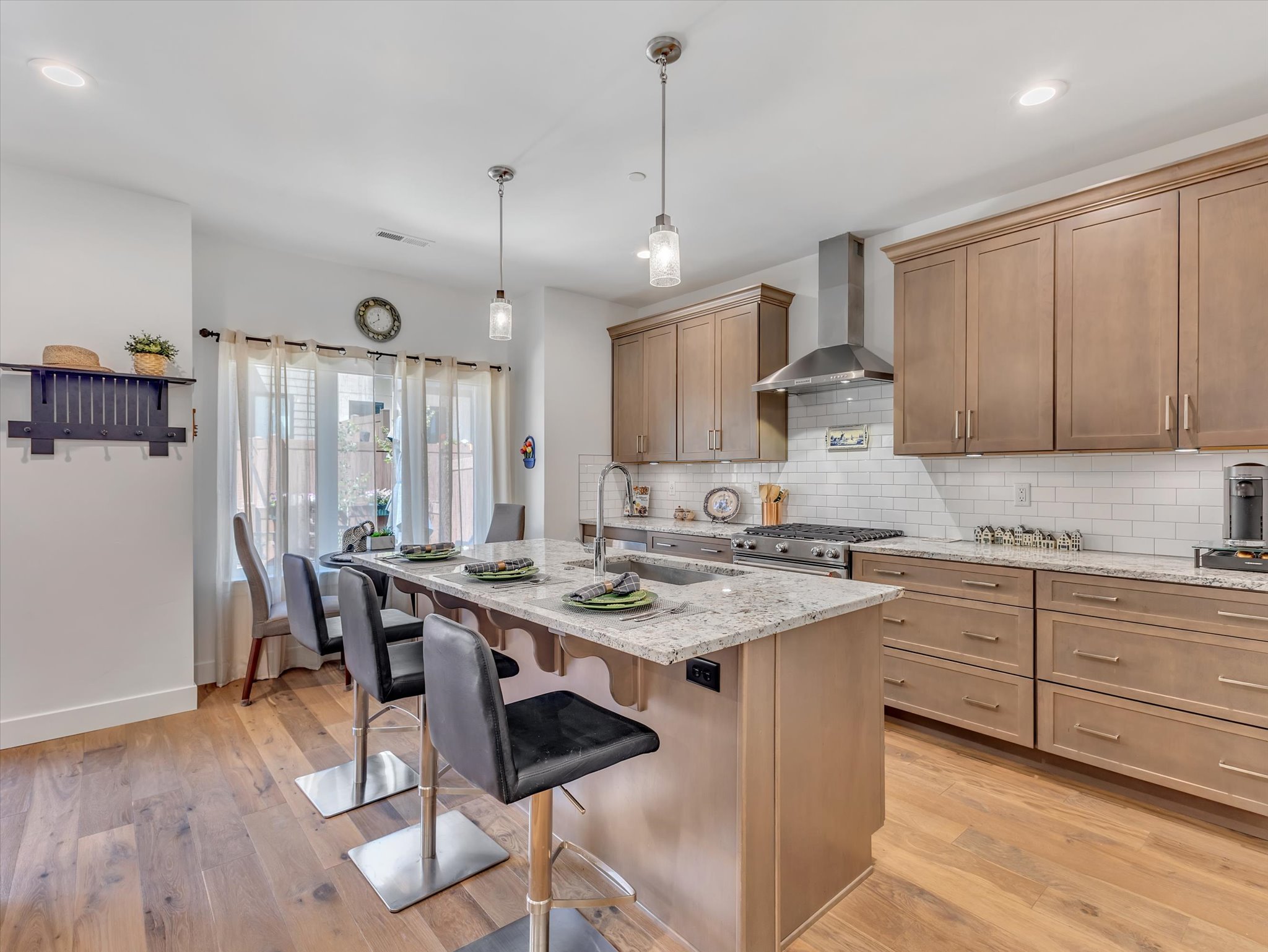 Gourmet kitchen featuring a large central island with seating, stainless steel appliances, extensive cabinetry, light-toned countertops, and wood-finish flooring