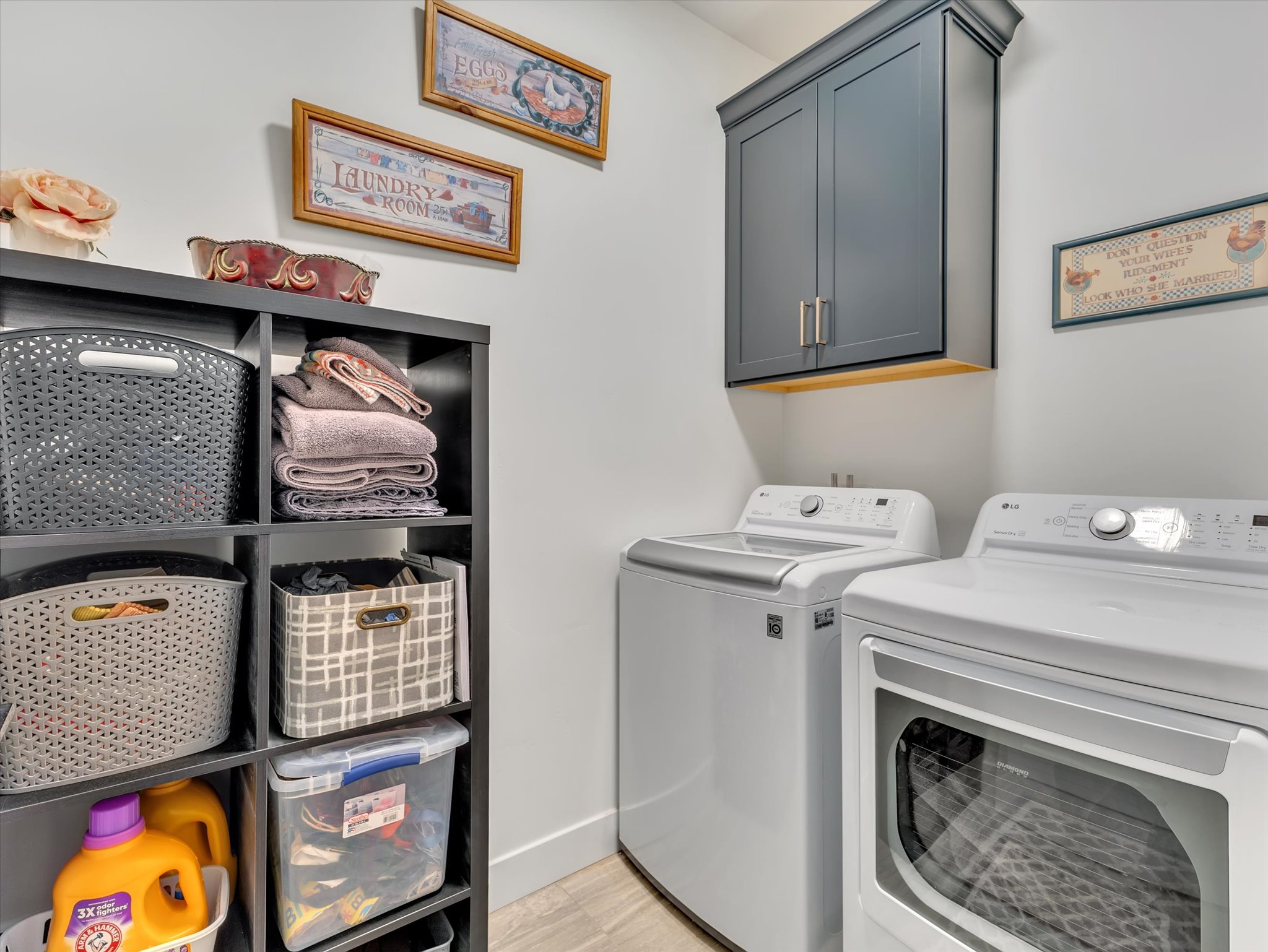 Dedicated laundry area featuring a wall-mounted cabinet with modern hardware, a front-loading dryer, and a top-loading washing machine