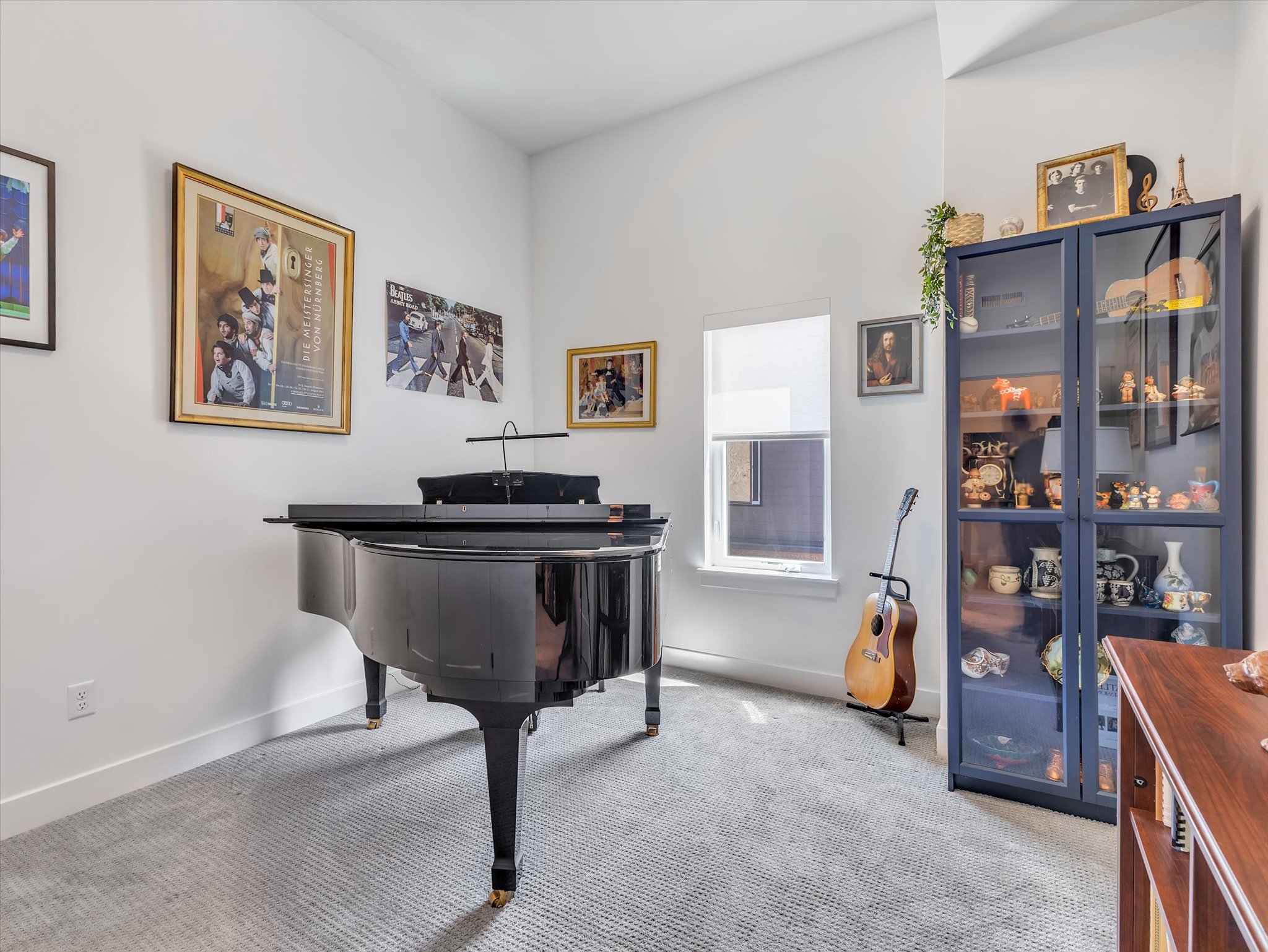 Dedicated space featuring light gray carpet flooring, white walls, and a window with a roller shade