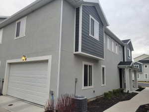 Exterior featuring stucco and horizontal siding, a two-car garage with an overhead door, and a covered entry
