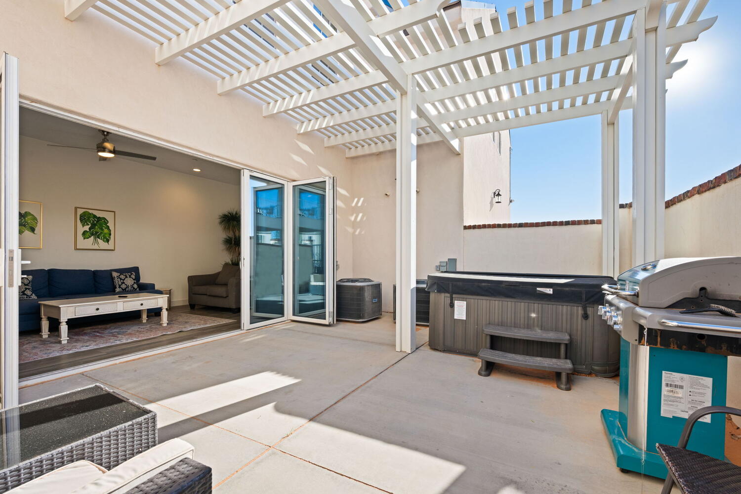 Spacious concrete patio featuring a white slatted pergola