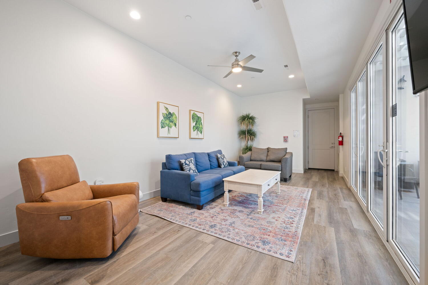 Spacious living area featuring light wood-finish flooring, recessed lighting, and a ceiling fan