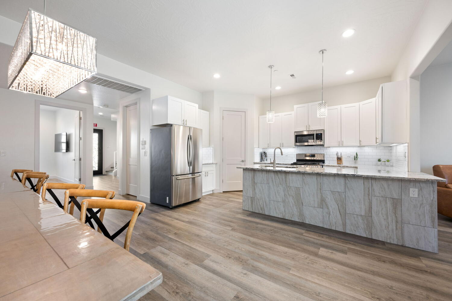 Open-concept kitchen and dining area featuring wood-finish flooring, white cabinetry, stainless steel appliances, a center island with pendant lighting, and recessed lighting