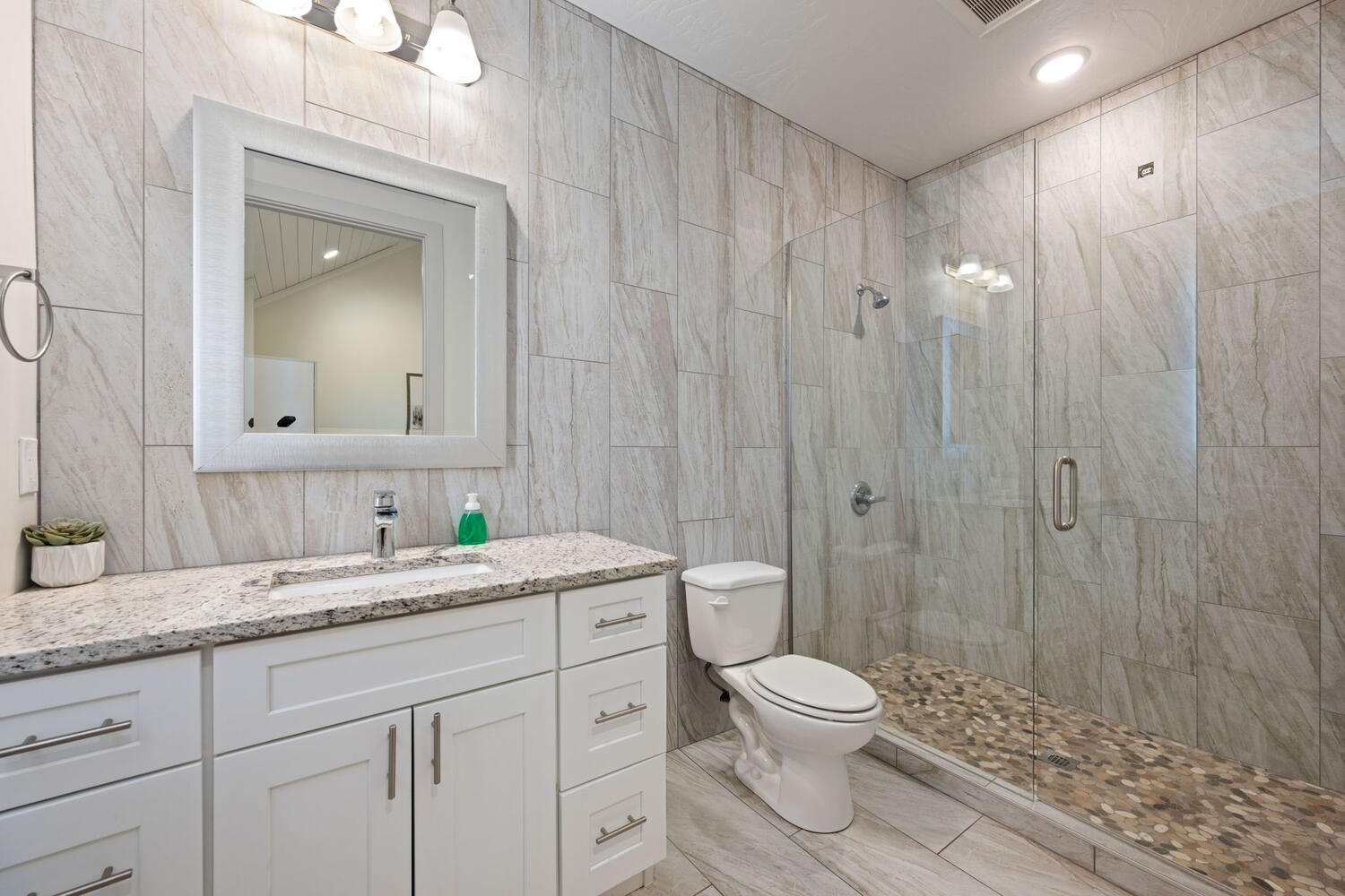 Bathroom featuring a full-width vanity with white cabinetry, a granite-finish countertop, and a rectangular undermount sink