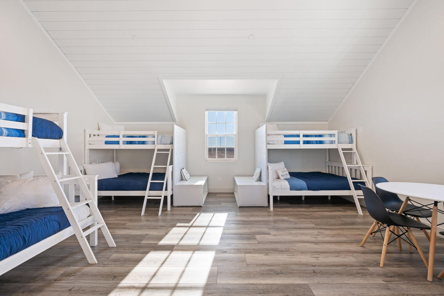 Spacious room featuring wood-finish flooring, white shiplap ceiling, and multiple bunk beds