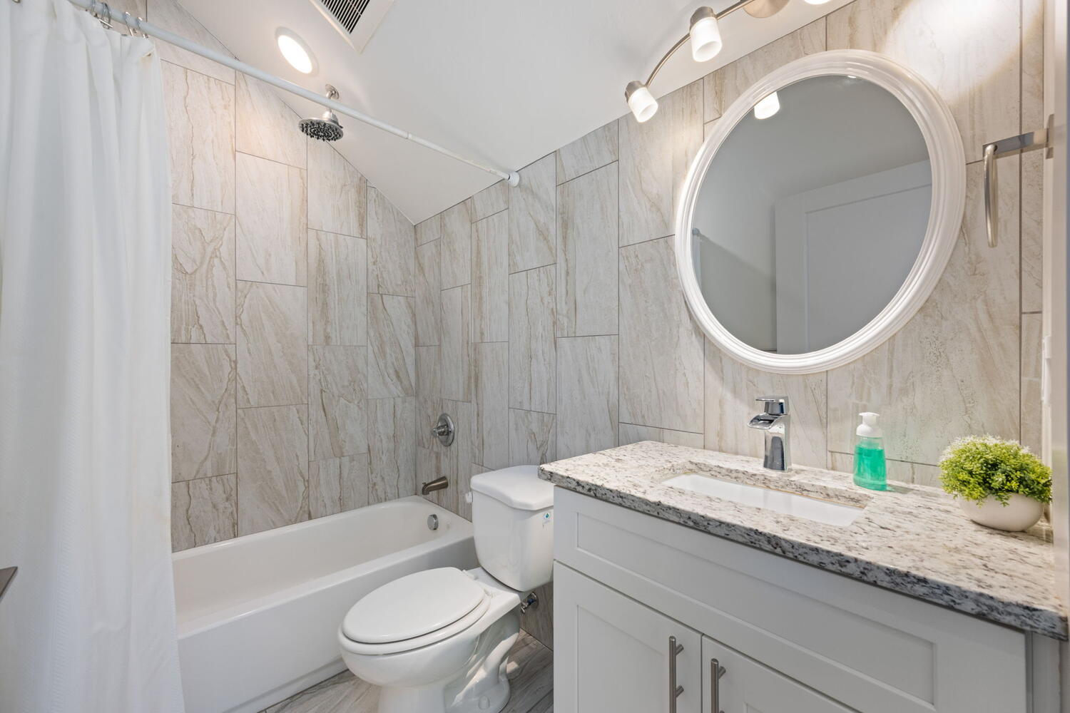 Vanity with a granite-style countertop, undermount sink, and chrome faucet