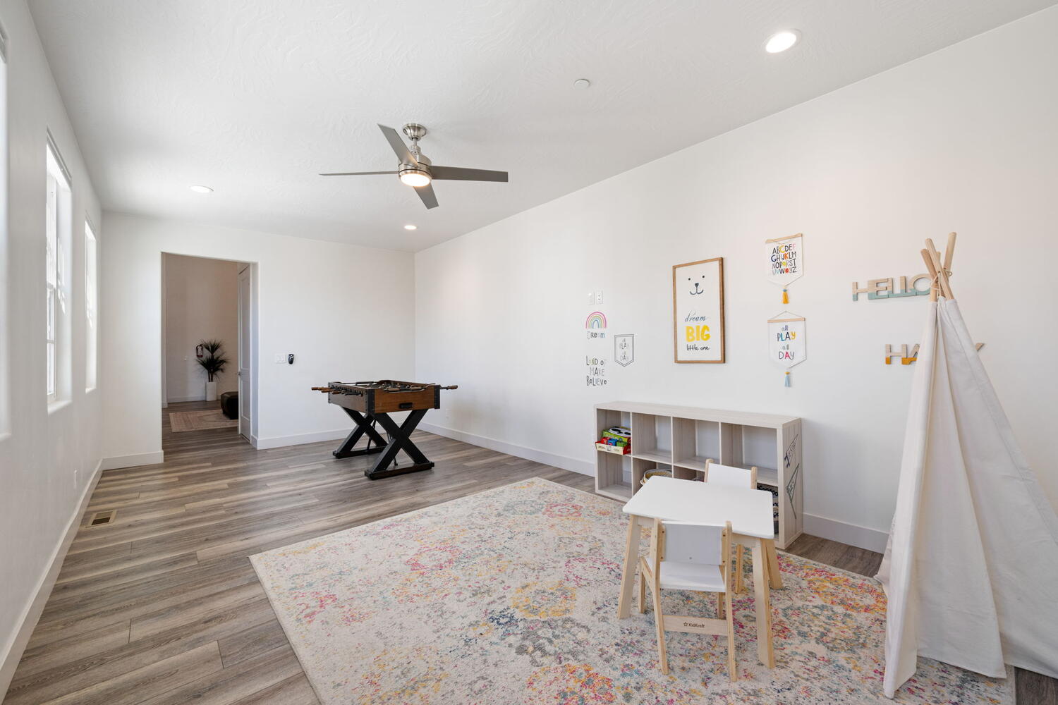 Spacious room featuring wood-finish flooring, recessed lighting, a modern ceiling fan, and multiple windows
