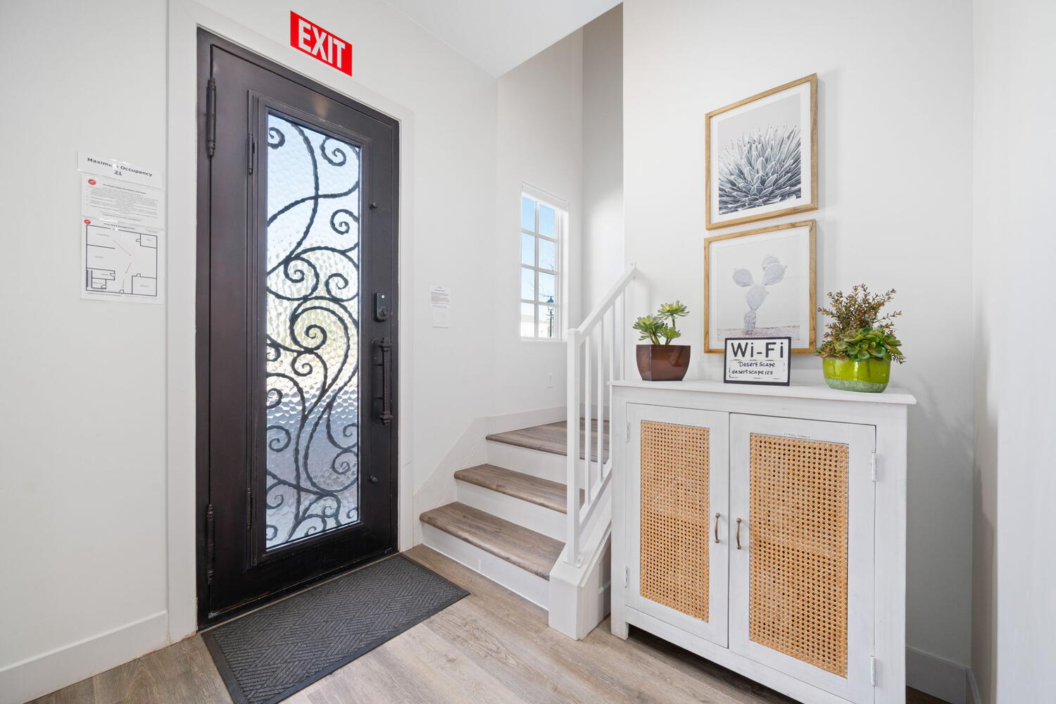 Entryway featuring a dark-finish door with decorative glass, wood-finish flooring, white baseboards, and a staircase with white risers and wood treads
