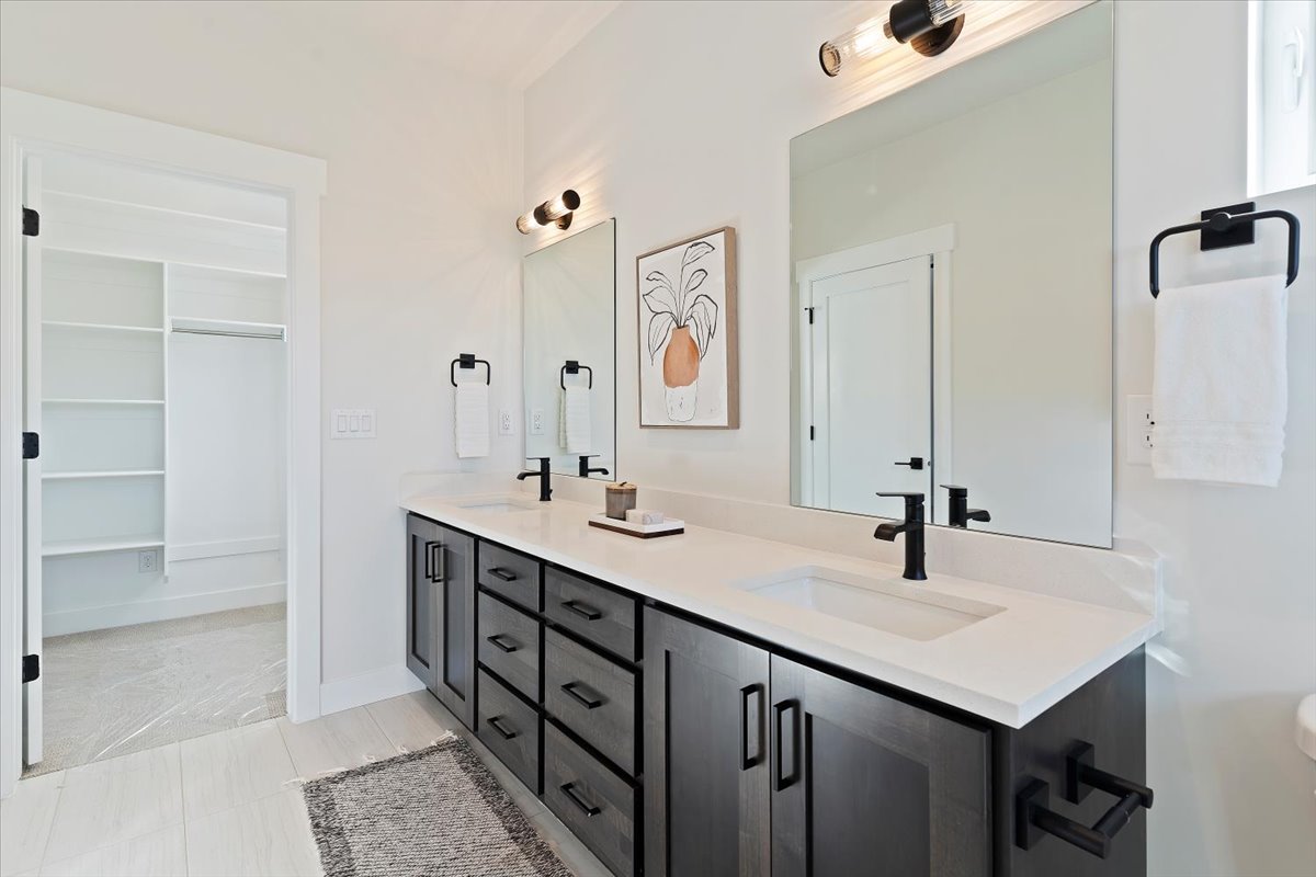 Dual vanity featuring dark wood-finish cabinetry, white countertops, and matte black fixtures
