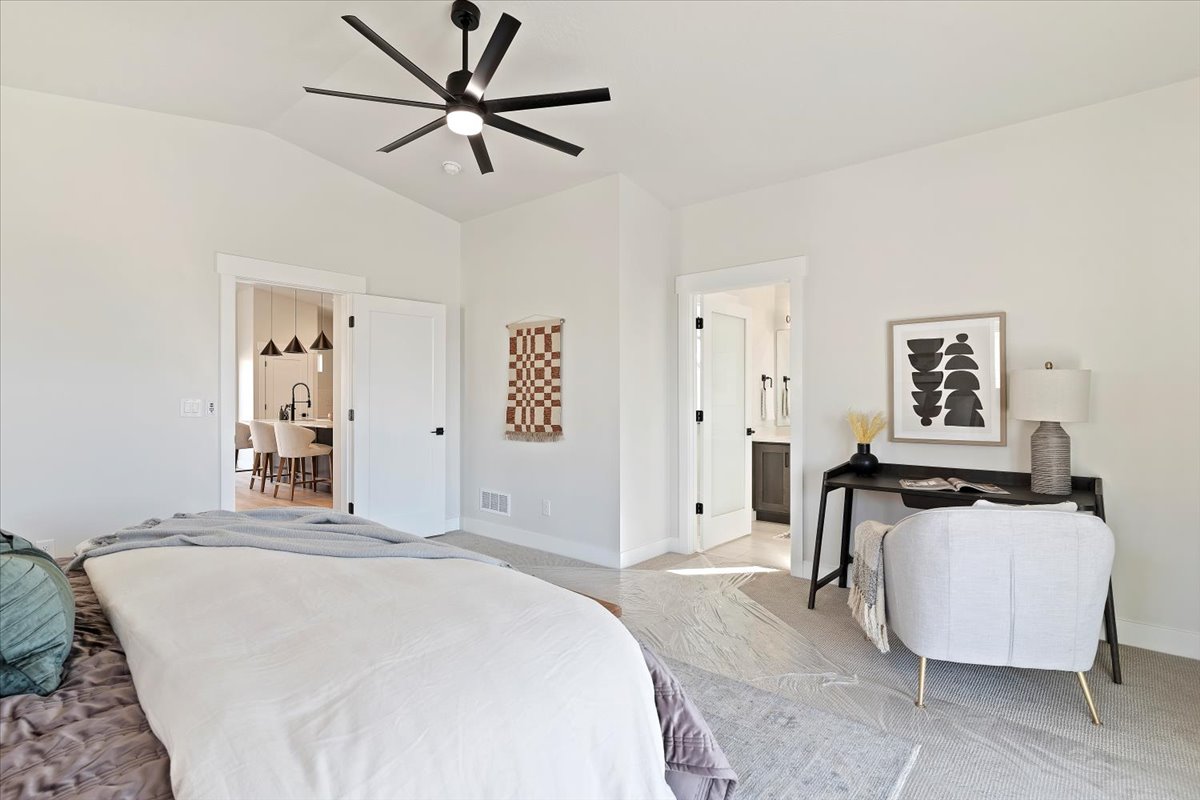 Light-filled bedroom featuring a modern black ceiling fan, vaulted ceiling, and neutral carpeting