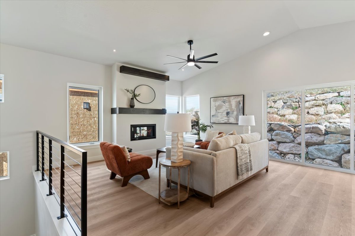 Vaulted ceilings enhance this living area featuring wood-finish flooring and a stone accent wall