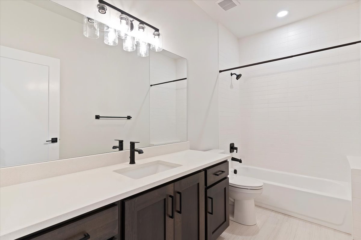 Bathroom featuring a dark wood-finish vanity with a light-toned countertop, an undermount sink, and a black-finish faucet