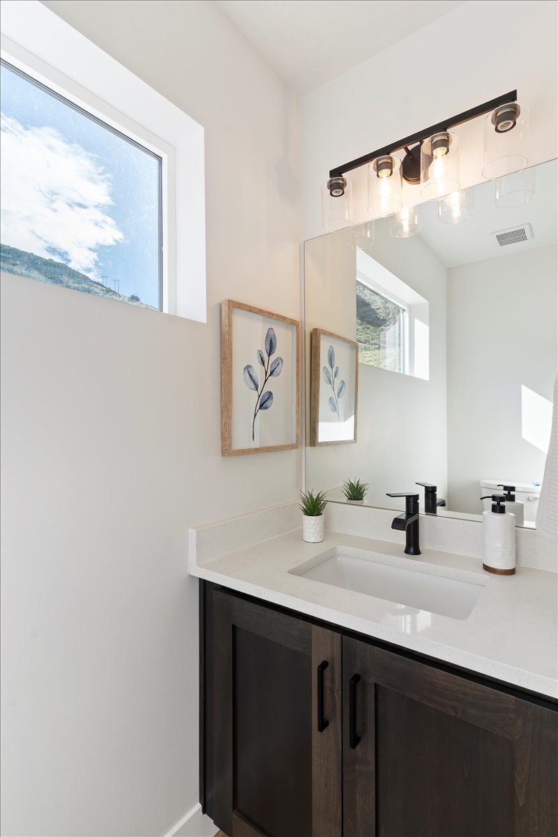 Bathroom vanity with dark wood-finish cabinetry, white countertop, and integrated rectangular sink