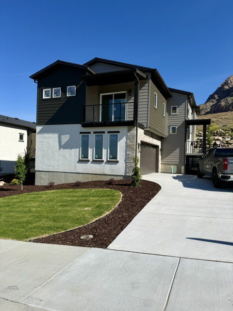 Contemporary multi-level residence featuring a dark gray and white exterior with stone accents