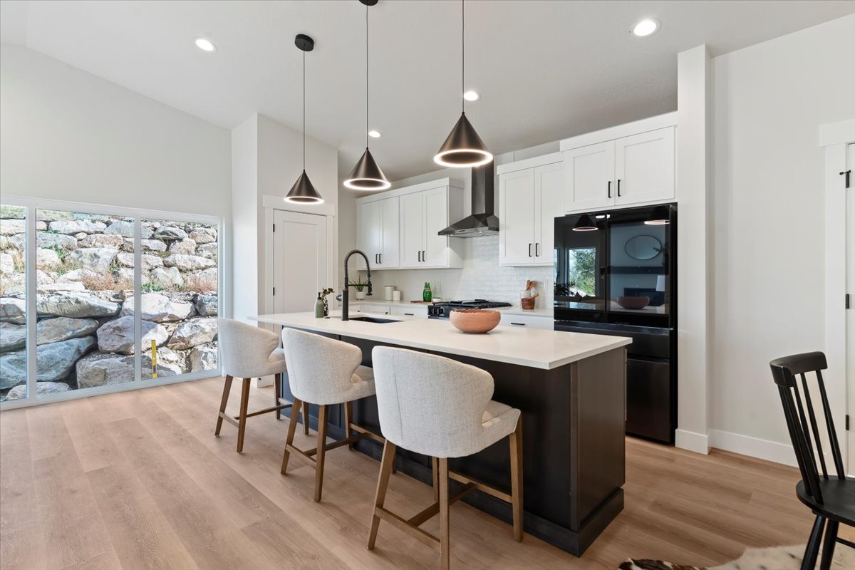 Contemporary kitchen featuring a large center island with seating, white shaker cabinetry, stainless steel appliances, and wood-finish flooring