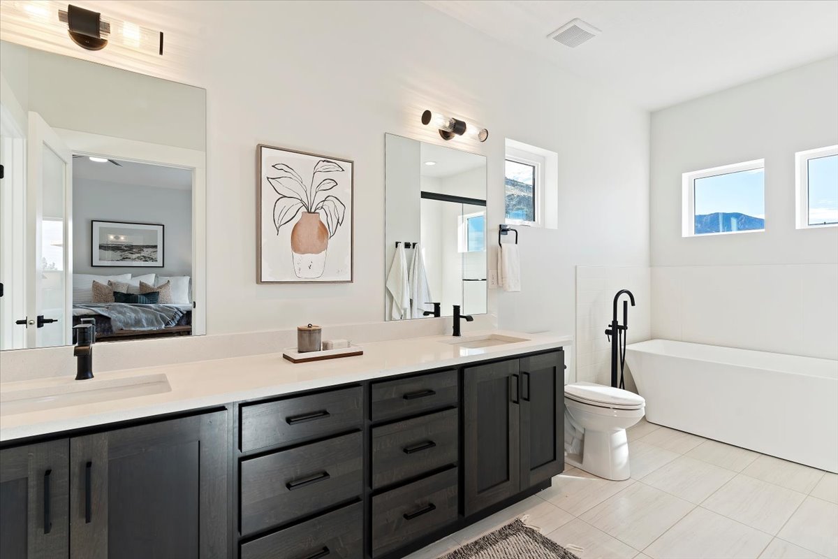 Double vanity featuring dark wood-finish cabinetry, white countertops, and matte black fixtures
