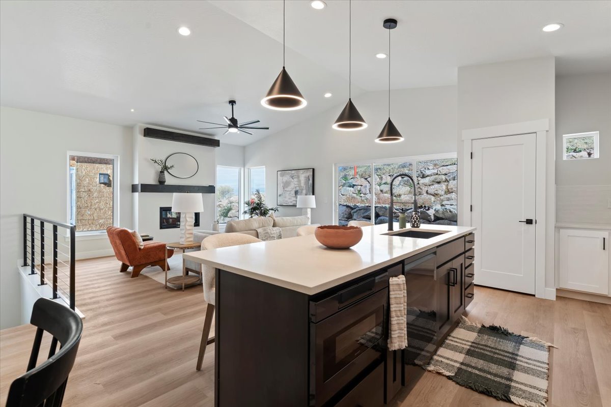 Open-concept living space featuring a central kitchen island with a dark finish and light-colored countertop, complemented by modern pendant lighting