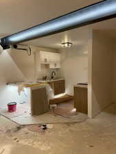 Kitchenette featuring white upper cabinetry, wood-finish lower cabinetry, a black faucet, and a subway tile backsplash