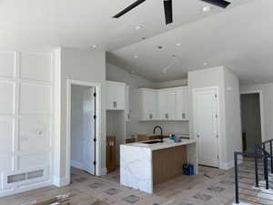 Modern kitchen featuring white shaker cabinetry and a waterfall island with stone-finish countertop