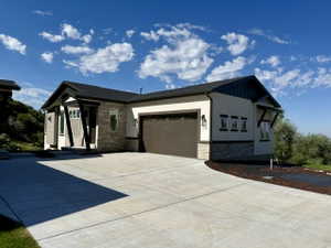 Contemporary facade featuring a prominent two-car garage, concrete driveway, and stone accents