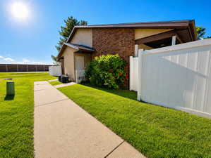 Exterior features include brick and stucco siding, a white PVC privacy fence, and a concrete walkway