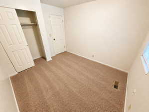 Room featuring neutral tone carpet, white baseboards, and textured wallpaper