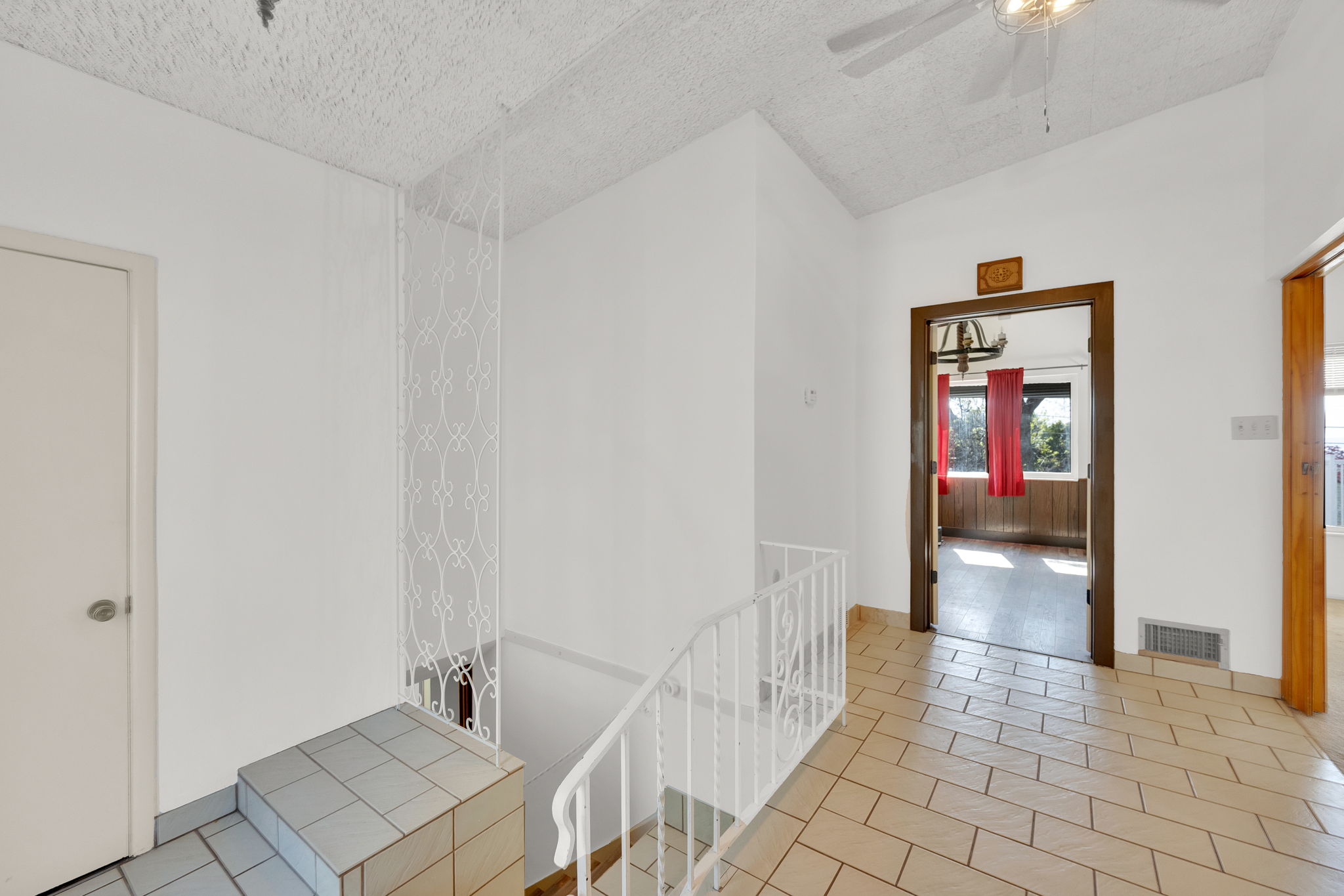 Hallway featuring light-toned tile flooring, white walls, and a textured ceiling