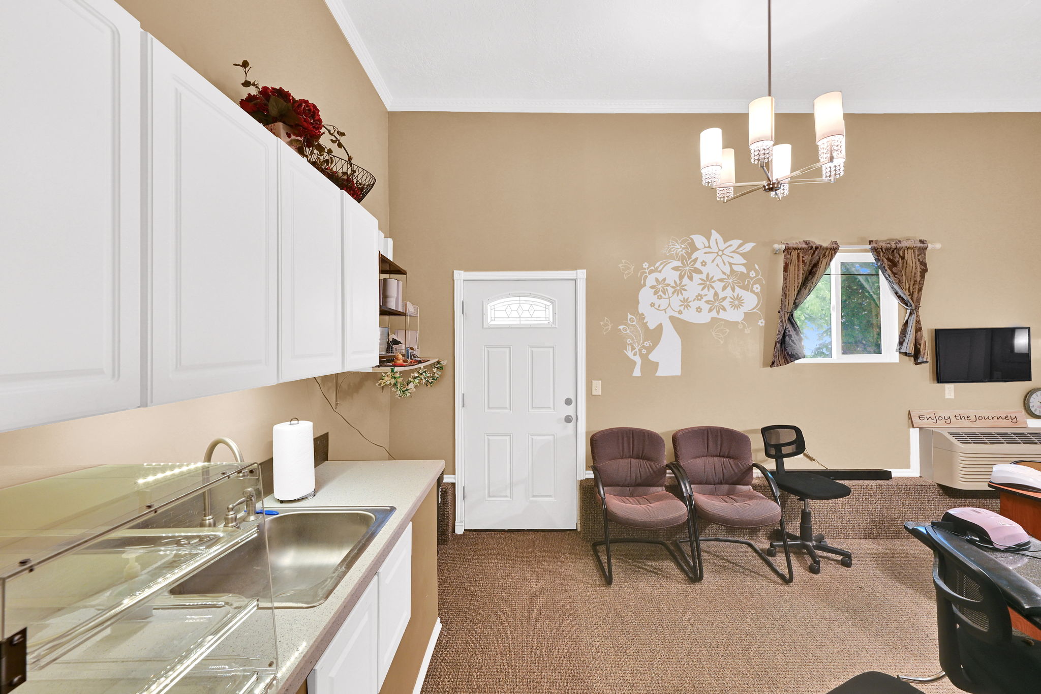 Interior space featuring high ceilings, white upper cabinetry, a stainless steel sink, and a light fixture with multiple sconces