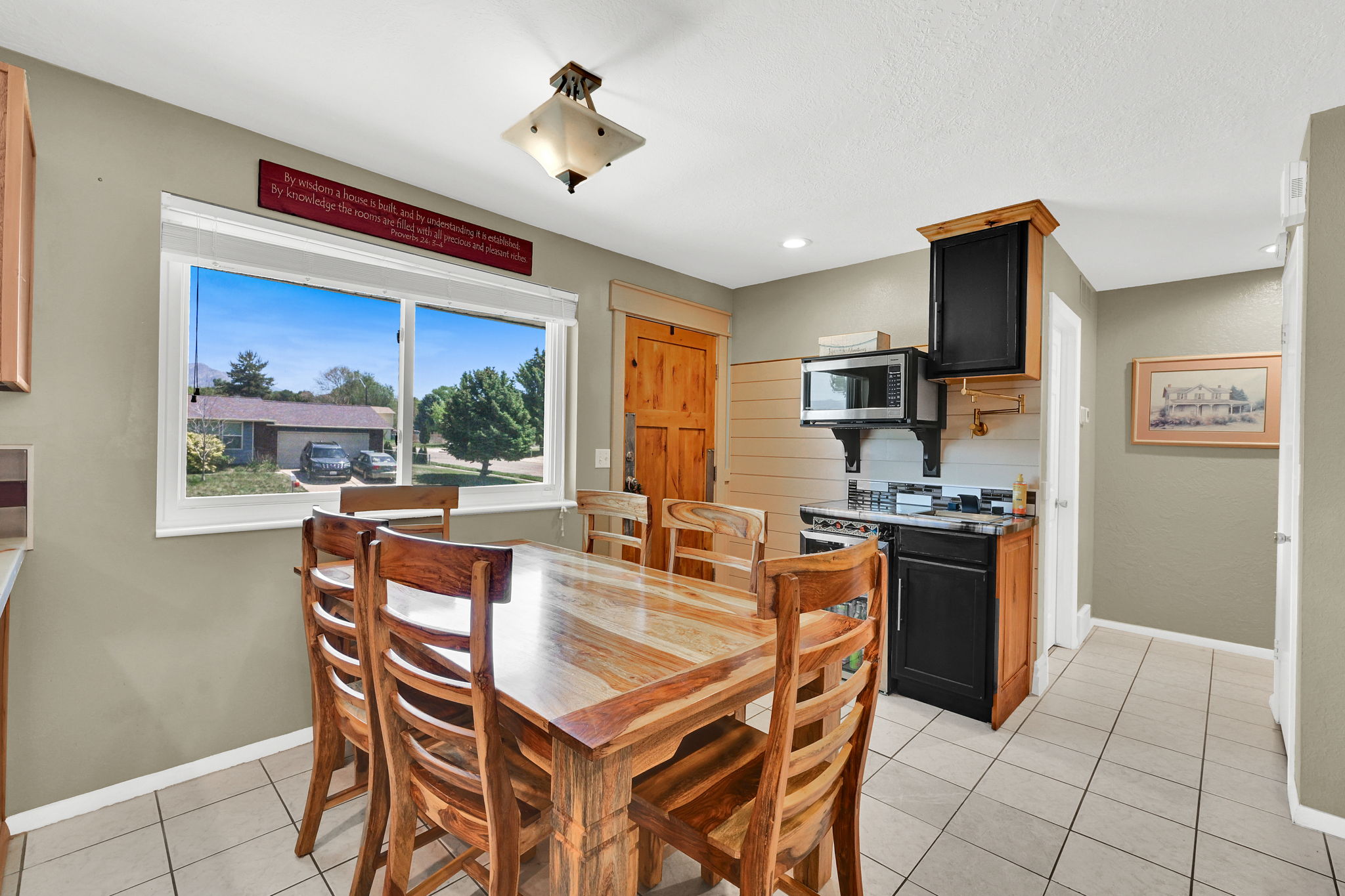 Eat-in kitchen featuring tile flooring, a large window, a built-in microwave, and a black range