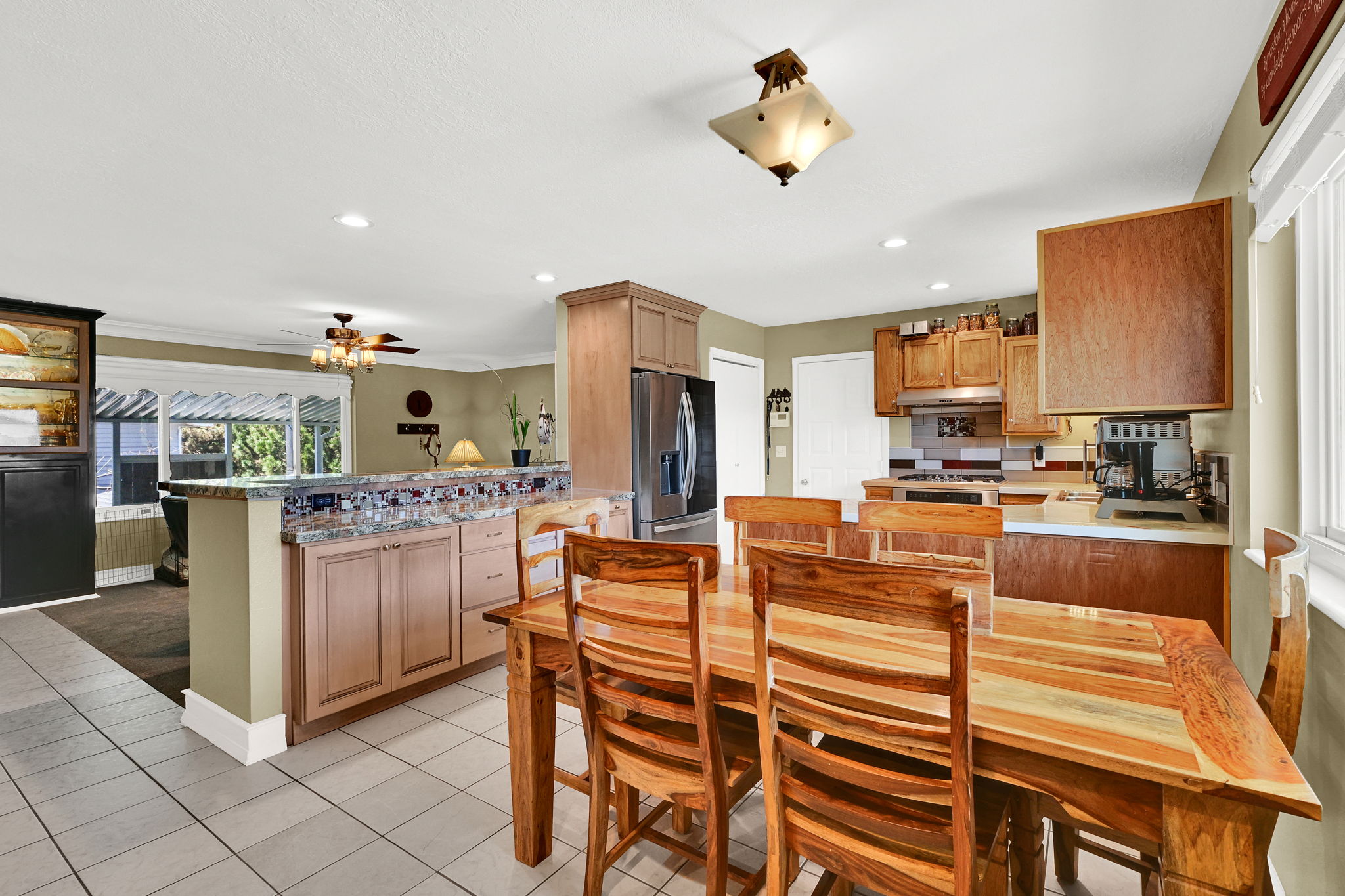 Spacious kitchen featuring tile flooring, light wood cabinetry, recessed lighting, and stainless steel appliances