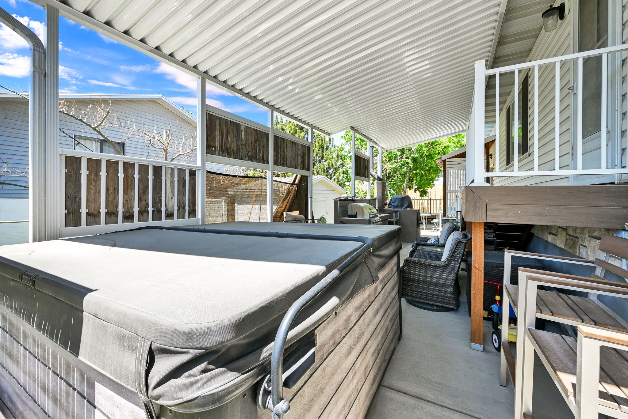 Covered patio featuring a hot tub, concrete flooring, and a corrugated metal roof