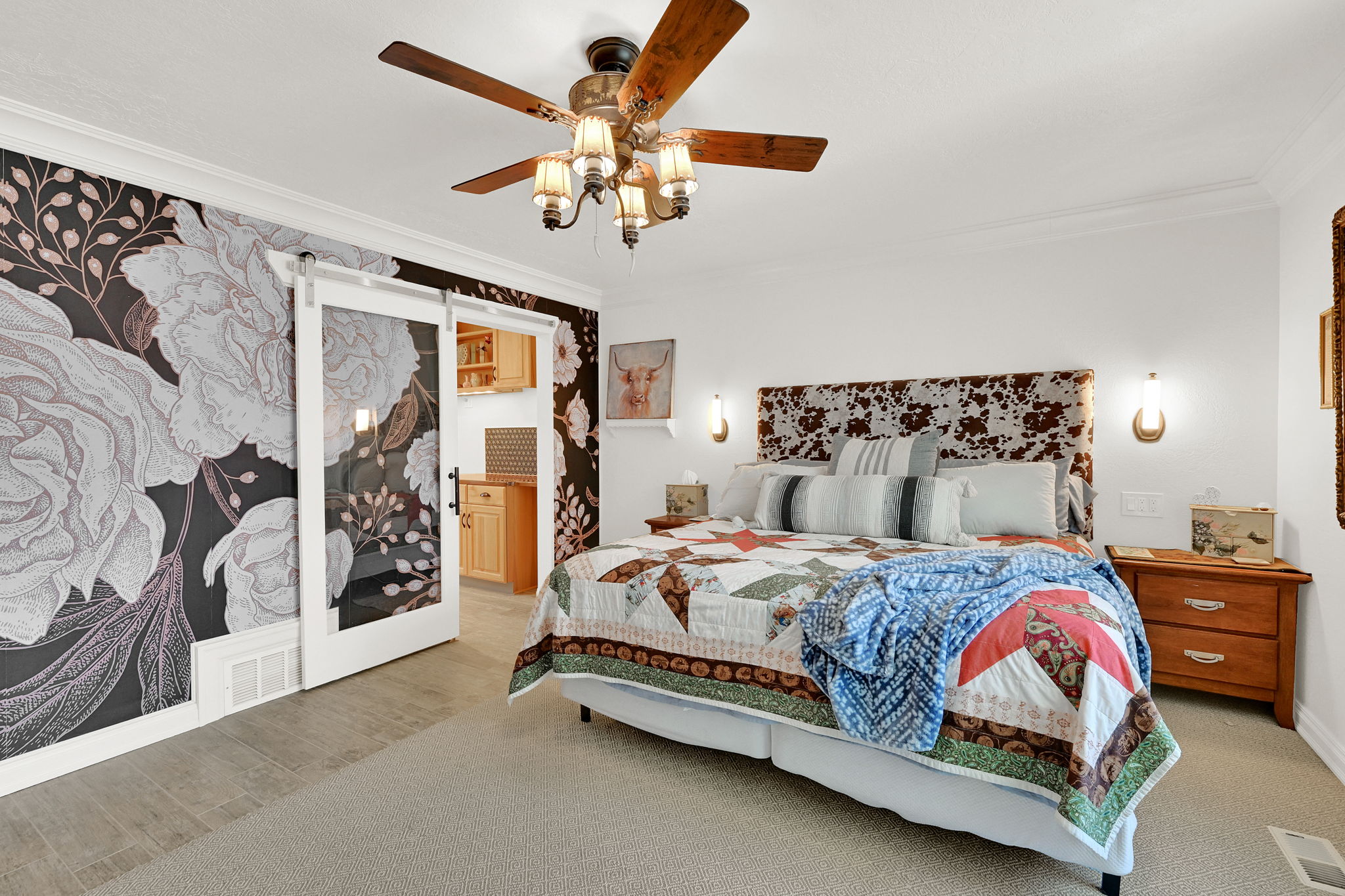 Spacious room featuring a decorative accent wall, a ceiling fan with integrated lighting, and a barn door entry to an adjacent space