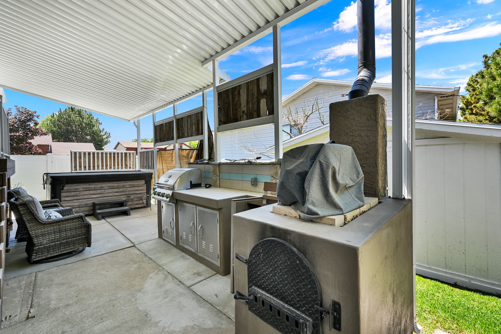 Covered patio featuring an outdoor kitchen with stainless steel cabinetry and an integrated grill, a built-in outdoor oven, a hot tub, and a concrete paver patio