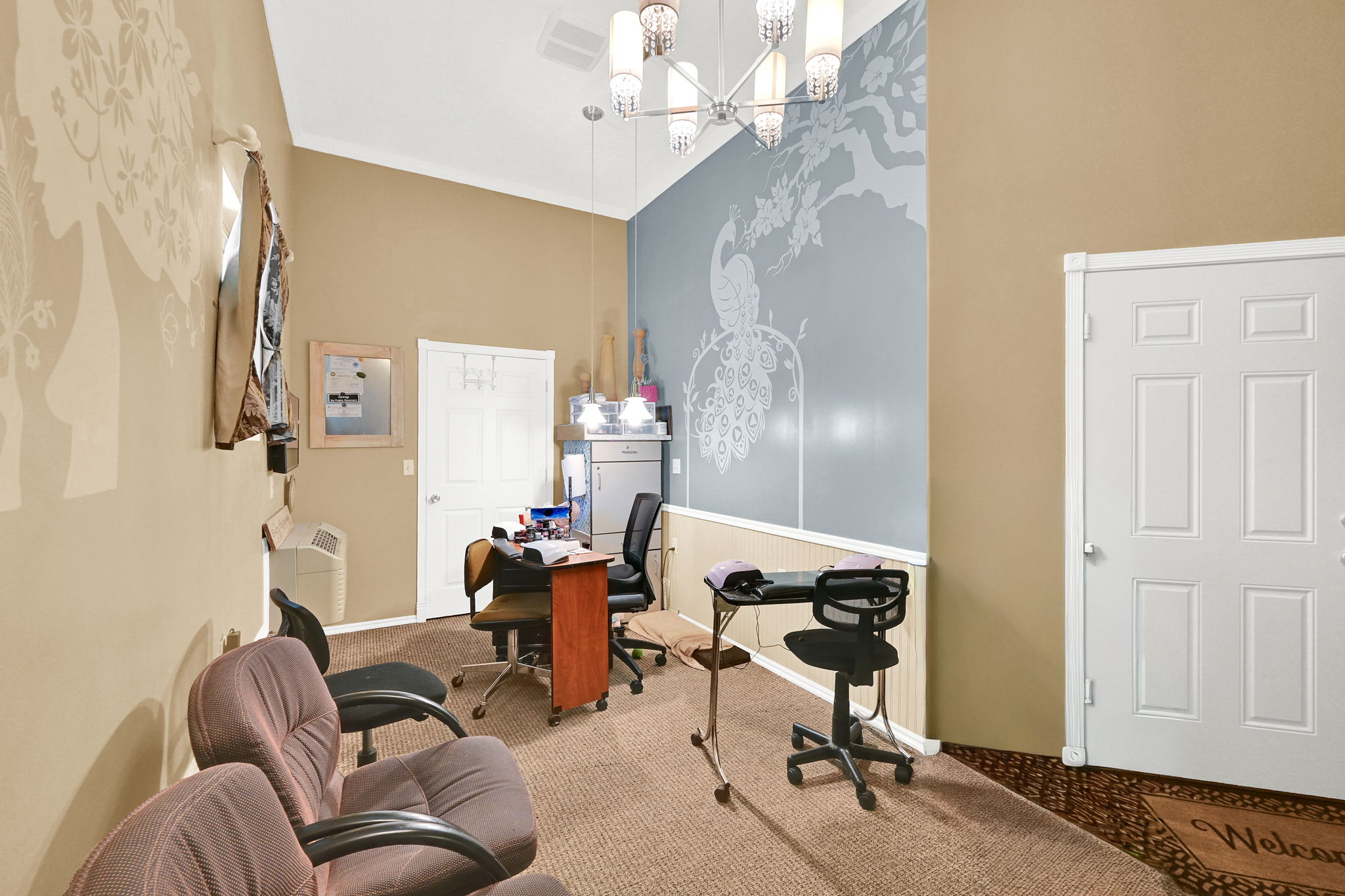 Interior space featuring high ceilings, a contemporary chandelier, two paneled doors, and a wall with decorative wainscoting