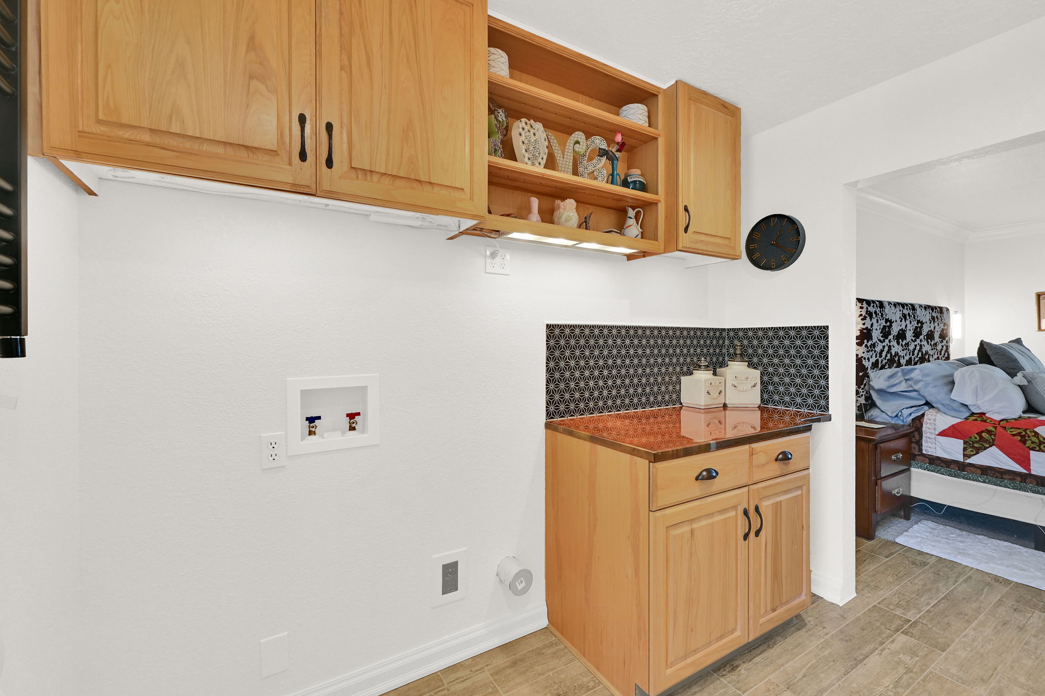 Utility area featuring light wood cabinetry, stone-look countertop, and a patterned tile backsplash
