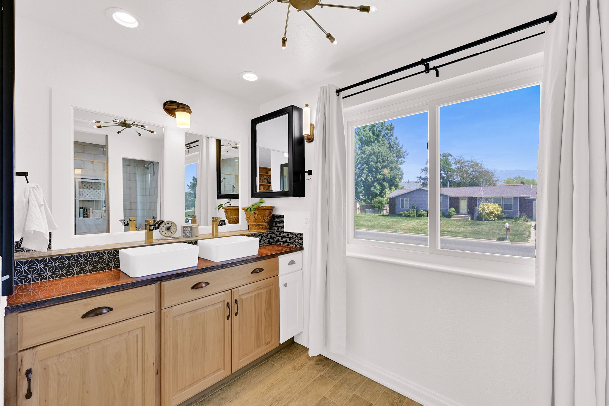 Double vanity featuring two vessel sinks, wood-finish cabinetry, and a patterned tile backsplash