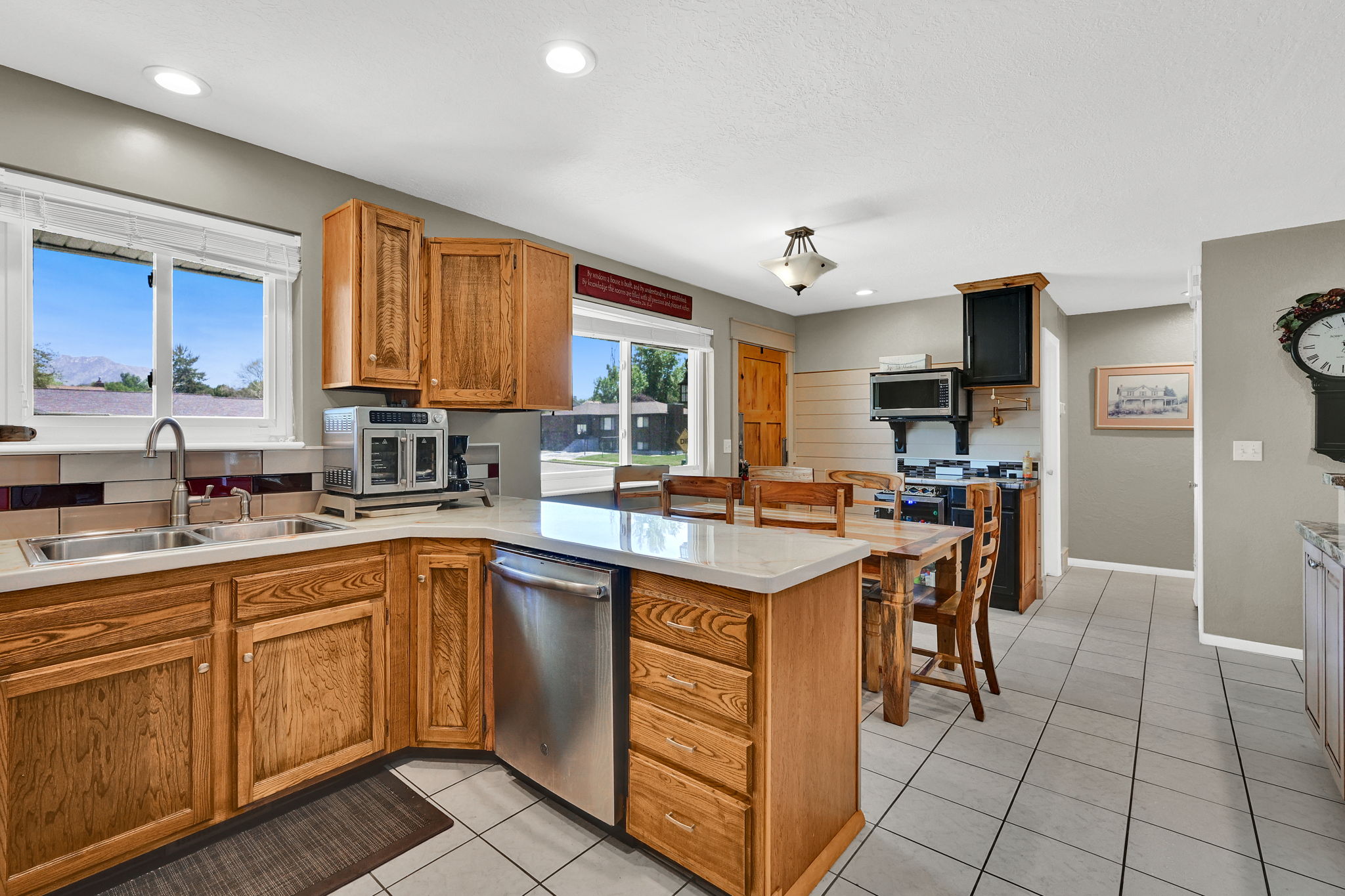 Kitchen featuring natural wood cabinetry, light countertops, stainless steel dishwasher, recessed lighting, and tile flooring