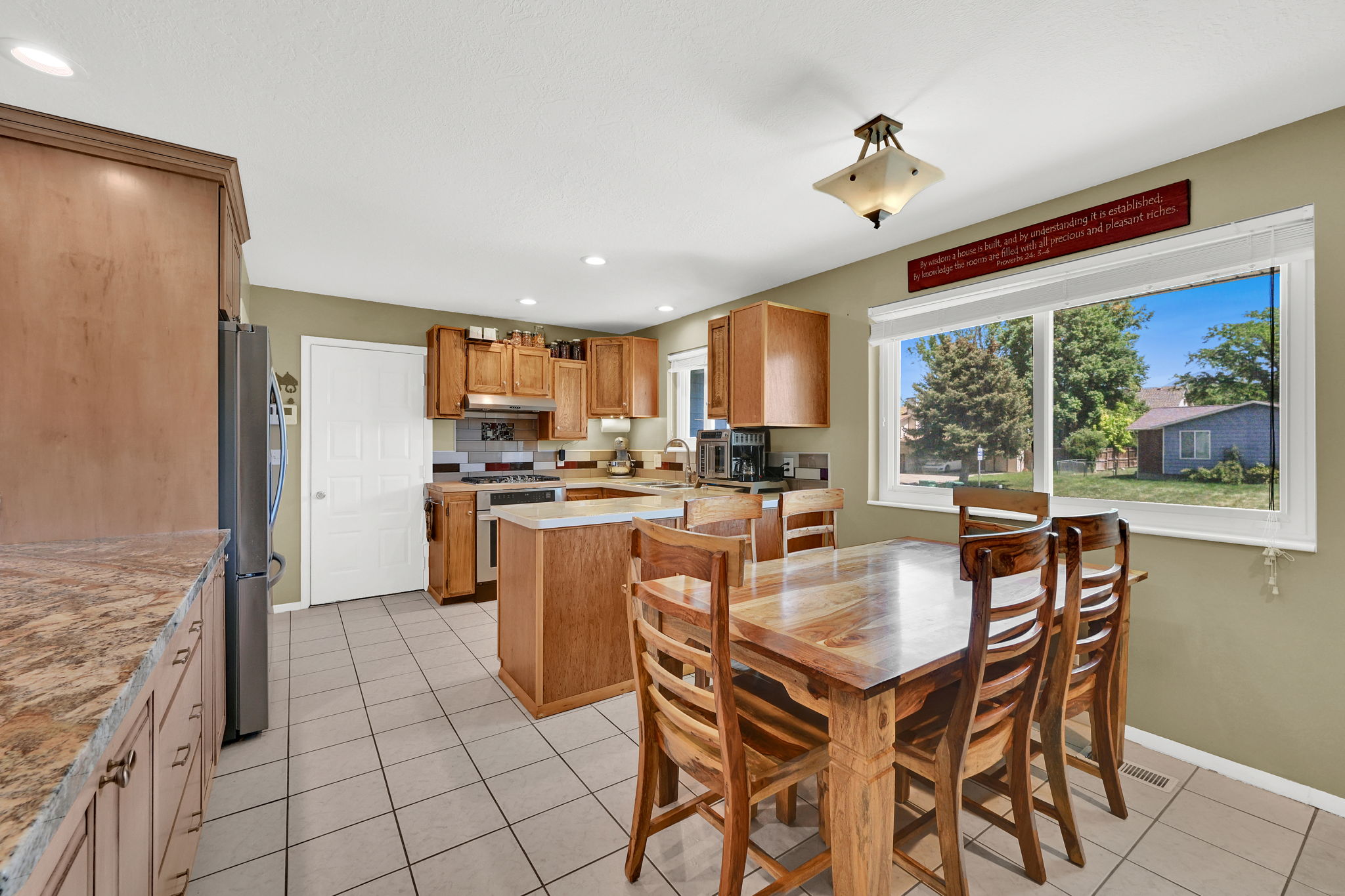 Spacious kitchen featuring tile flooring, wood cabinetry, stone-finish countertops, and stainless steel appliances