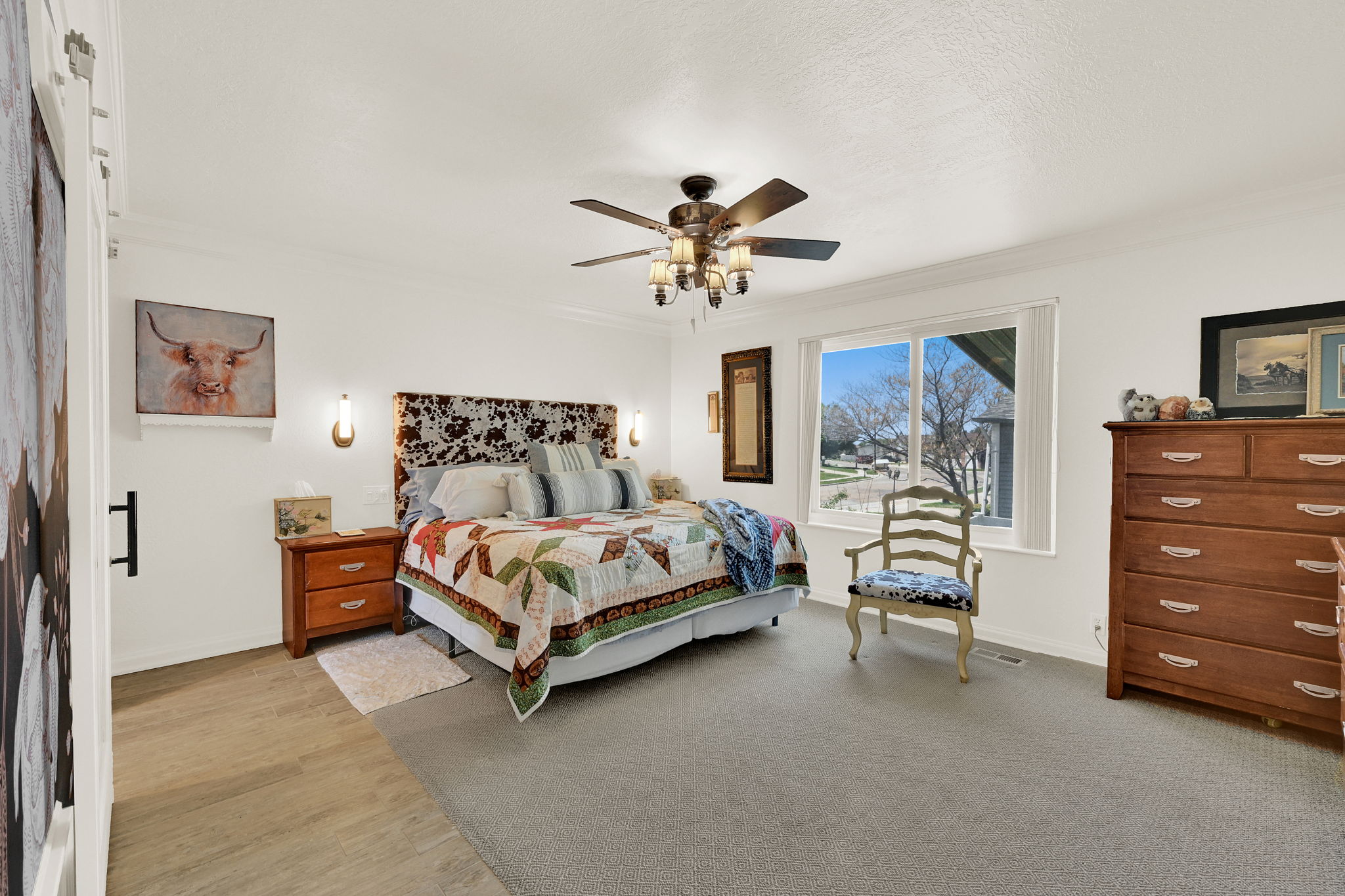 Expansive room featuring a large window, ceiling fan with integrated lighting, wall sconces, and crown molding