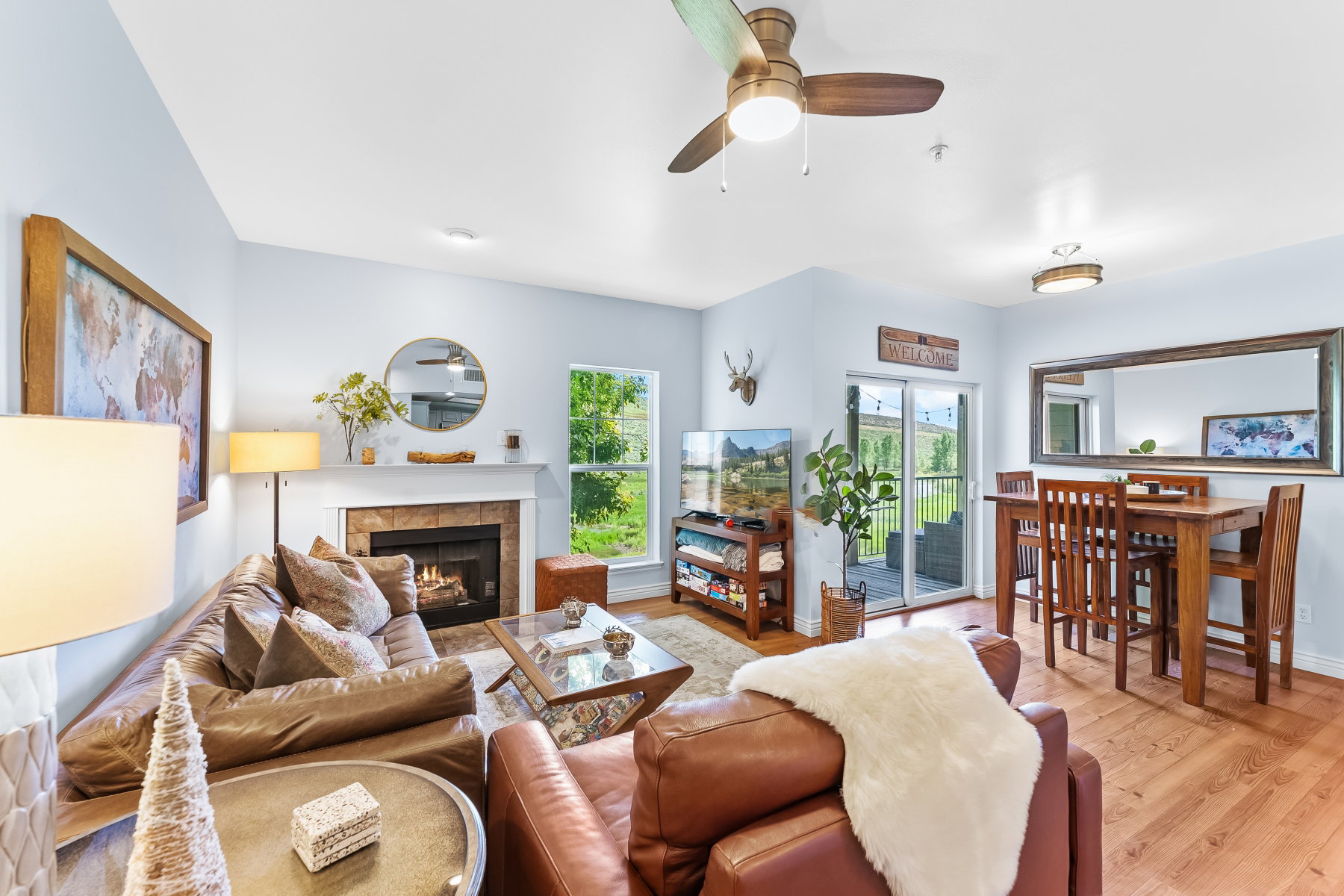 Spacious interior featuring wood-finish flooring, a fireplace with a stone surround and white mantel, and a sliding glass door opening to an outdoor area