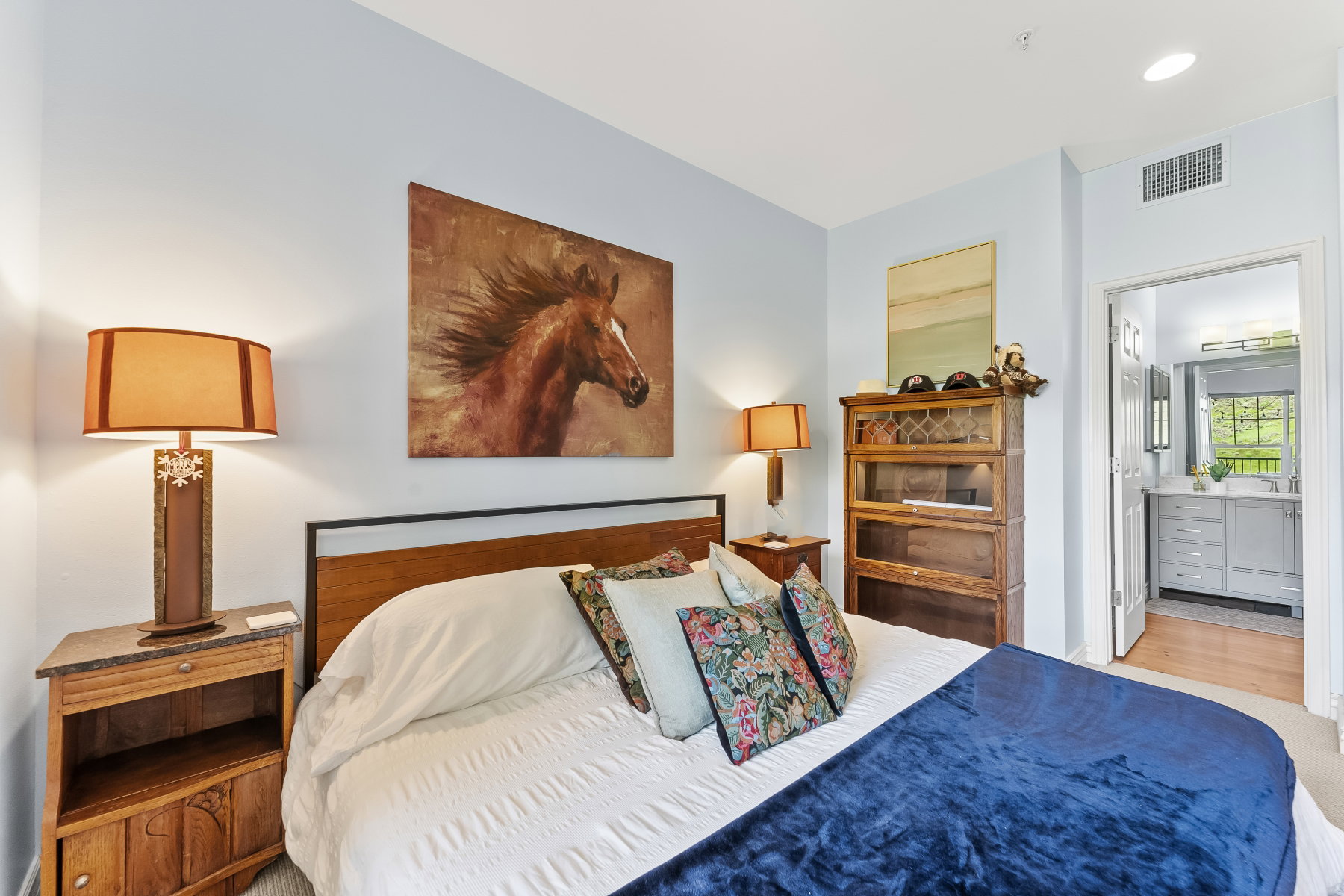 Carpeted bedroom with light blue wall paint and a wood-finish headboard