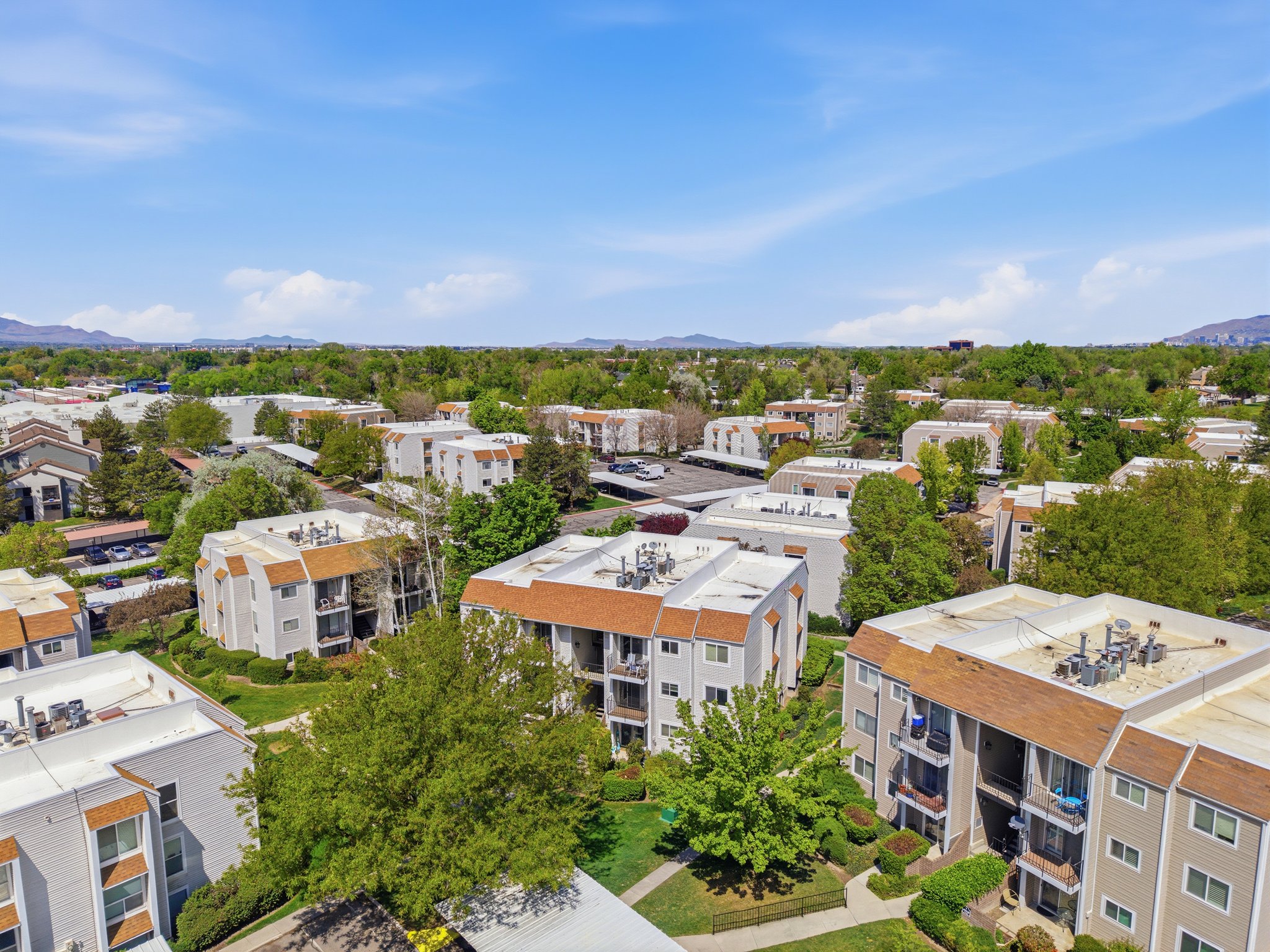 Aerial perspective showcasing a complex of multi-story residential buildings with pitched shingle roofs and private balconies