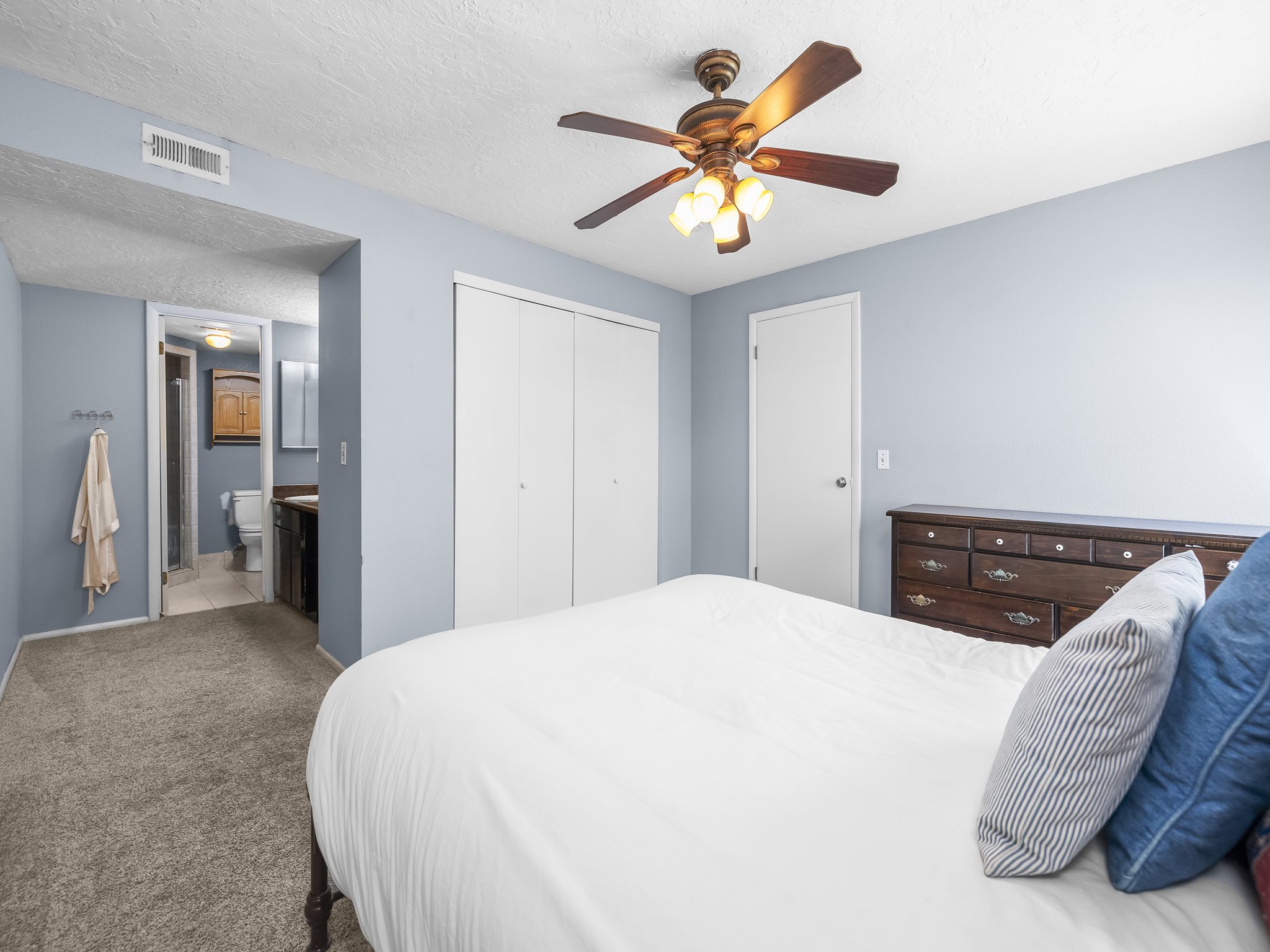 Bedroom featuring light blue walls, gray carpeting, and a ceiling fan with integrated lighting