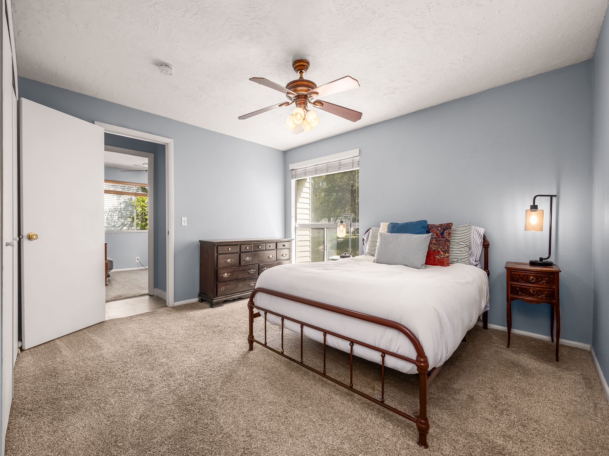 Bedroom featuring neutral-toned carpet flooring, light blue walls, and a ceiling fan with integrated lighting
