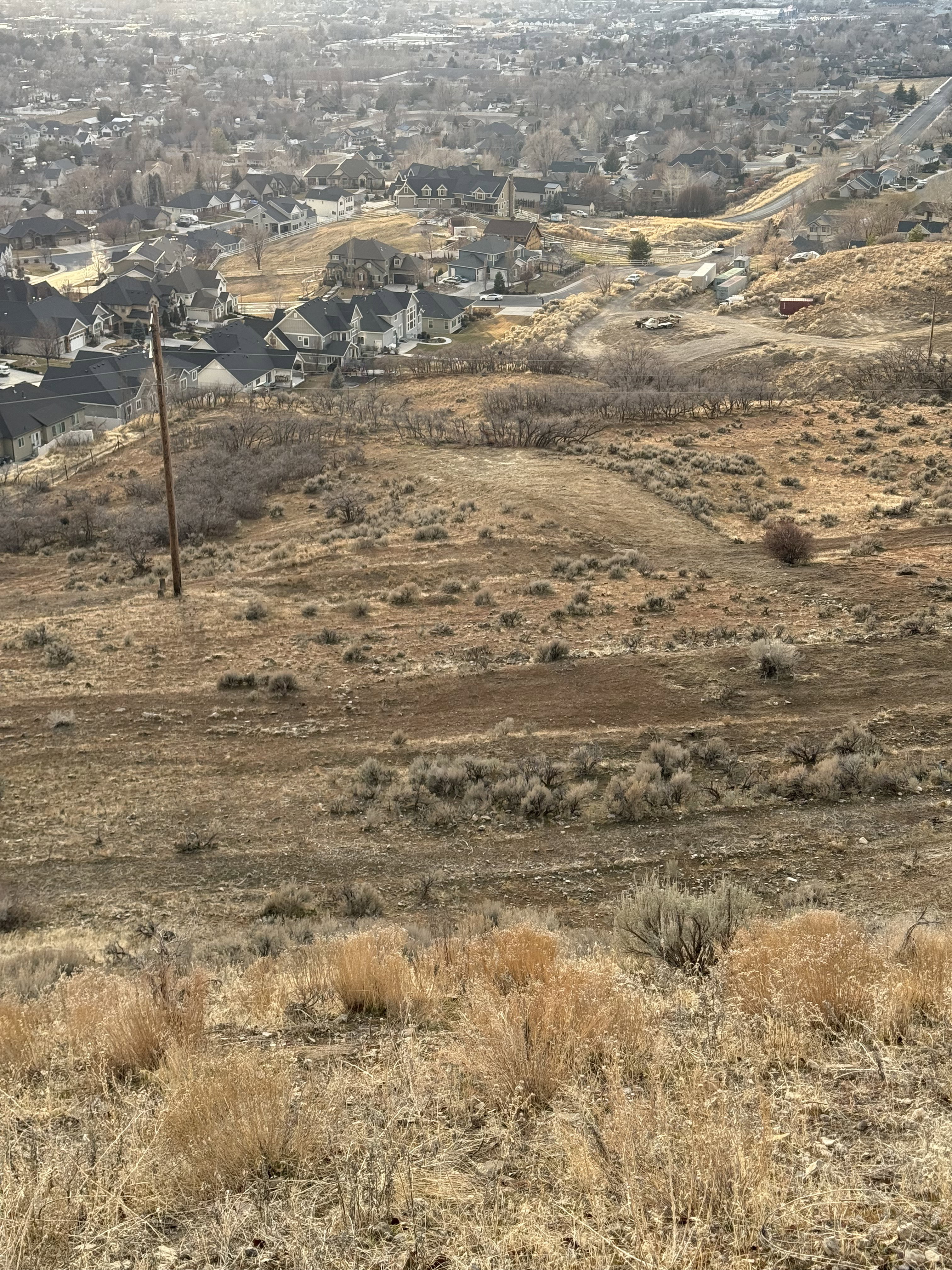 Sloping land featuring natural terrain with scattered brush and dry grasses